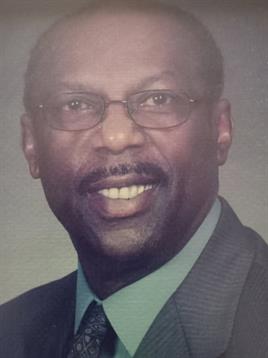 A confident man wearing glasses and a suit is smiling warmly, showcasing his professional demeanor.