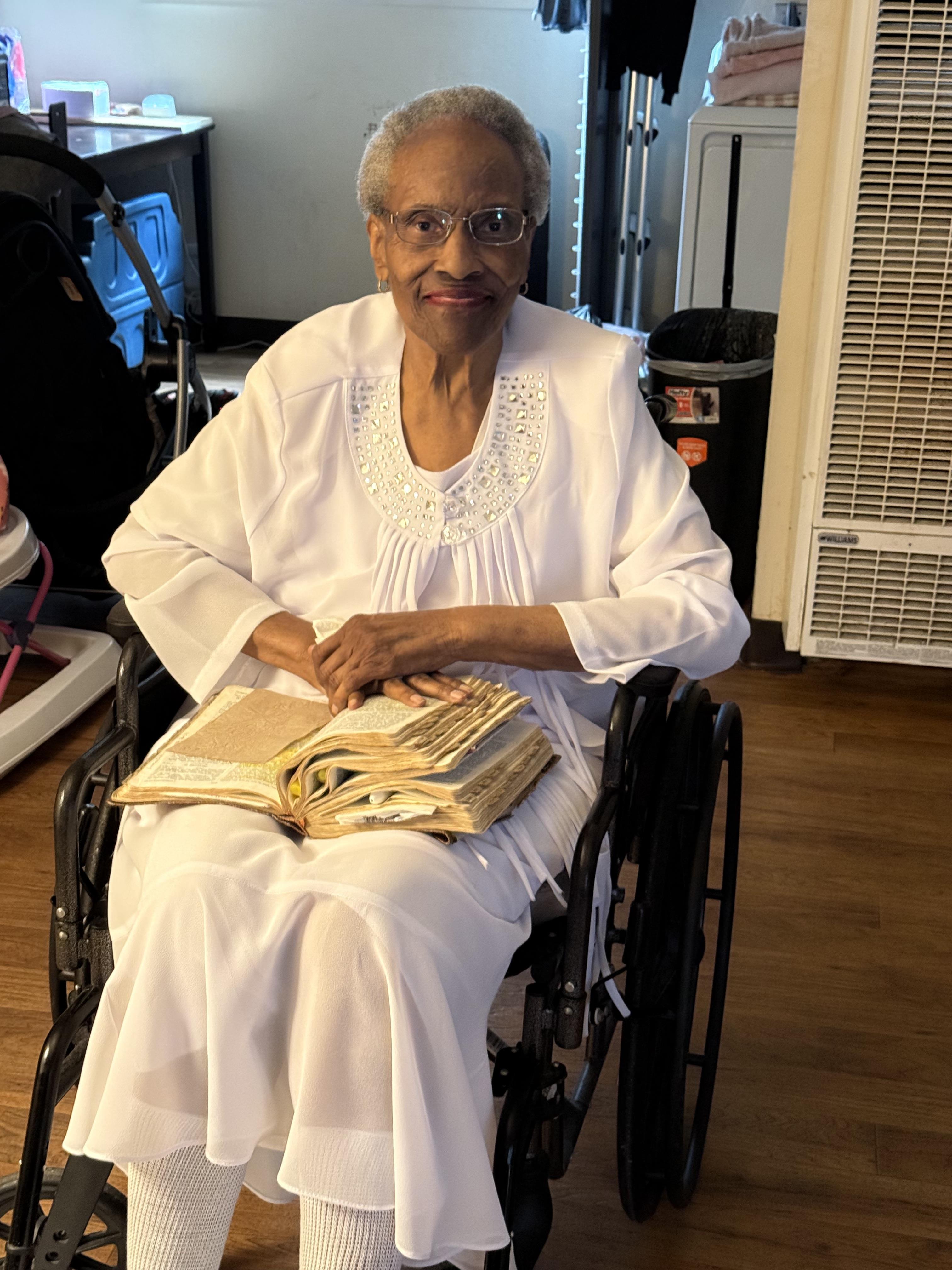 An old woman in a wheelchair holding a book