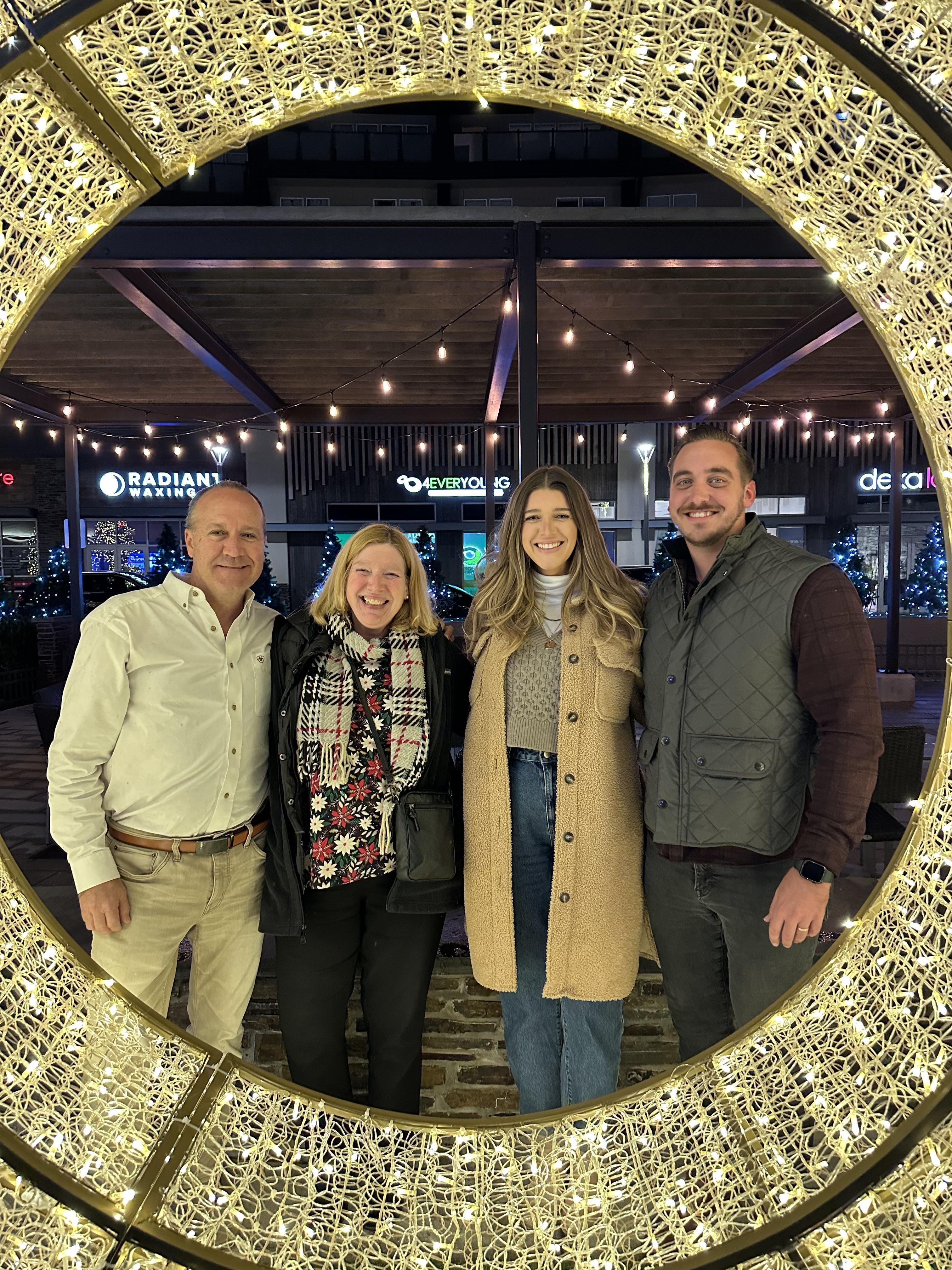 Friends gather for a joyful evening in a cozy, festive setting amidst twinkling lights.