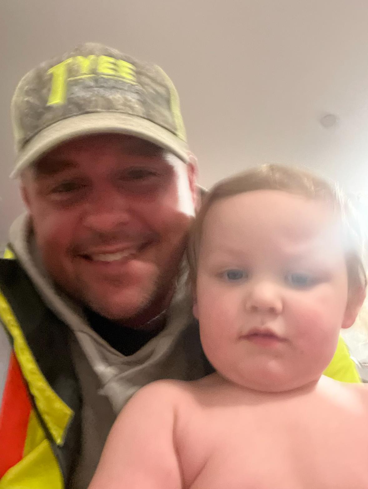 A father and his young child are smiling happily together in a well-lit indoor space.
