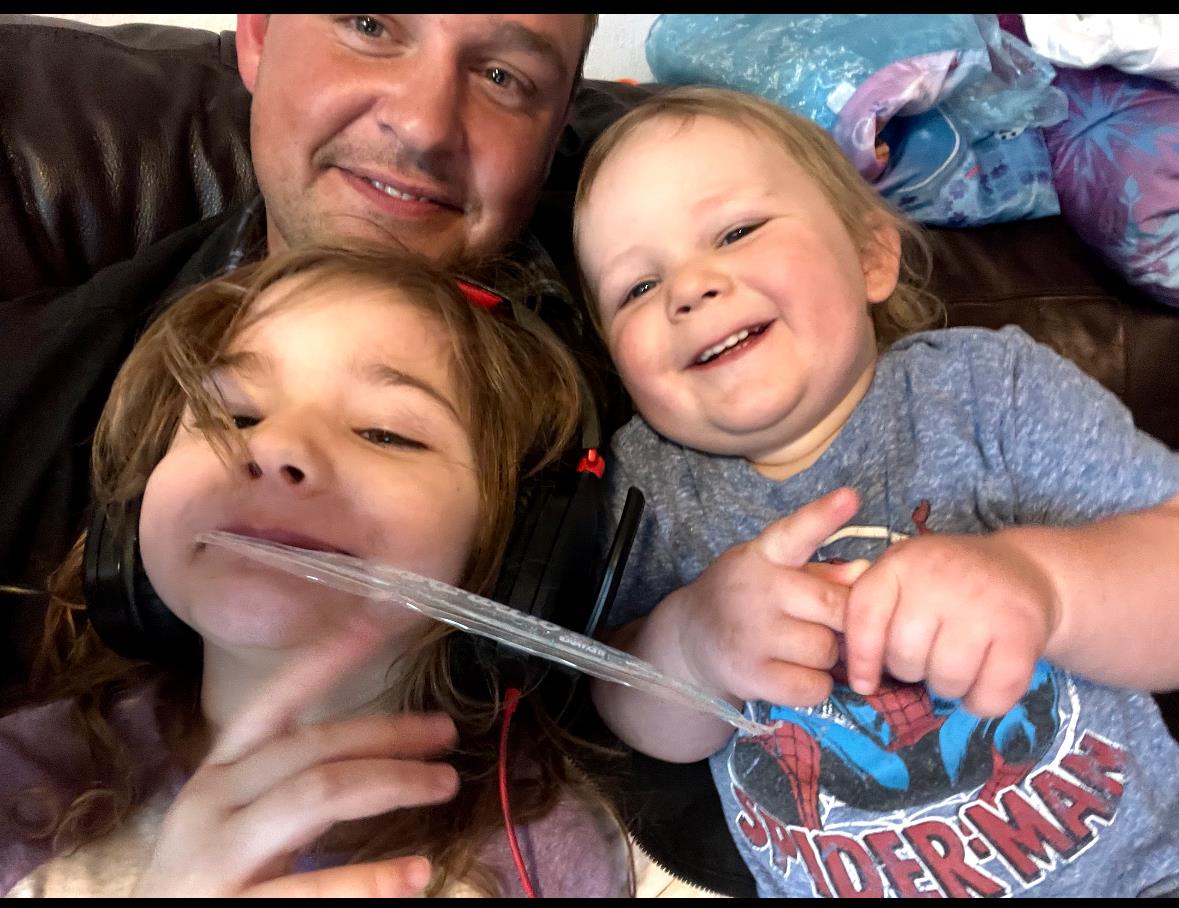 Children enjoy a lighthearted moment while playing with their father on the couch.