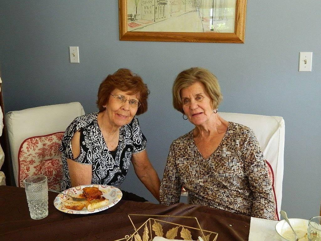 Two women share a meal and conversation at a dining table, enjoying each other's company.