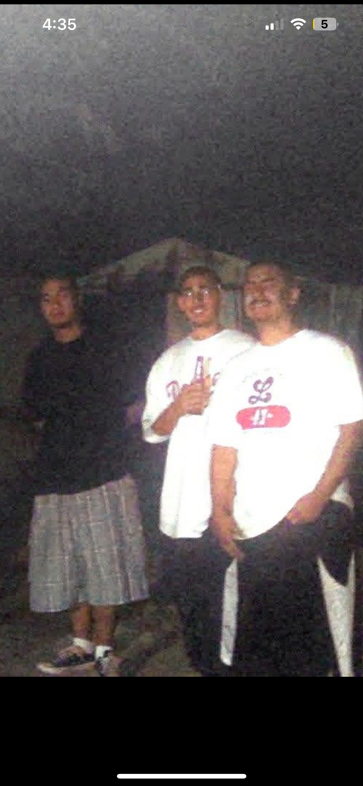 Three men pose together outdoors at night during a social gathering with friends.