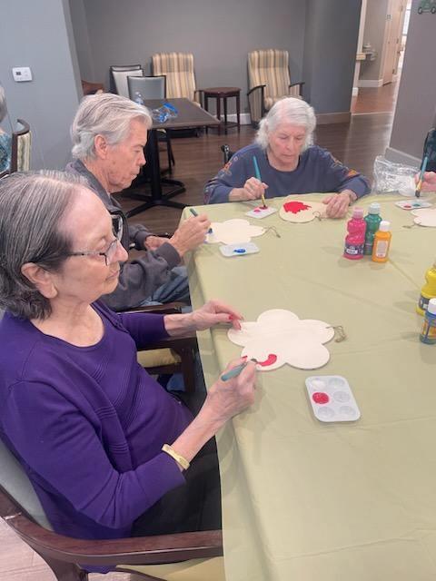 Group of older adults painting flower shapes at a community center, enjoying a creative afternoon.