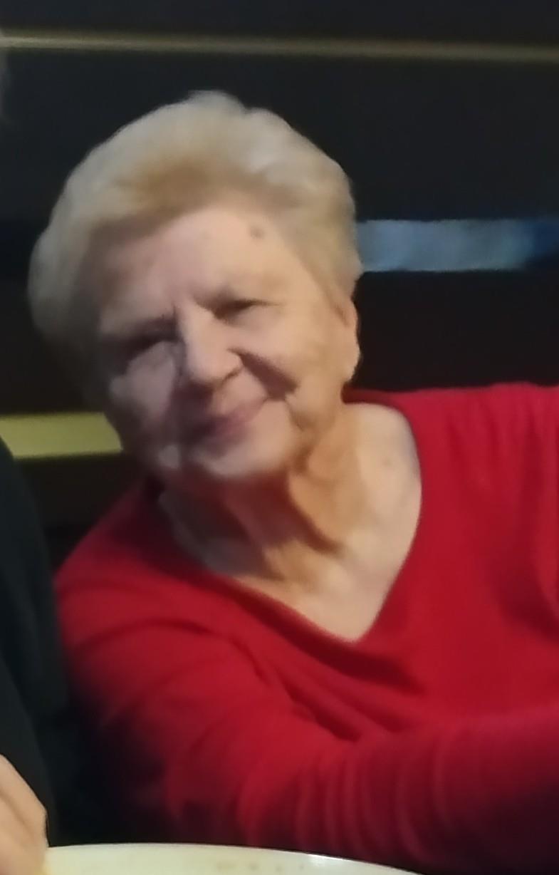 A warm-hearted elderly woman enjoys time with friends in a relaxed indoor environment.