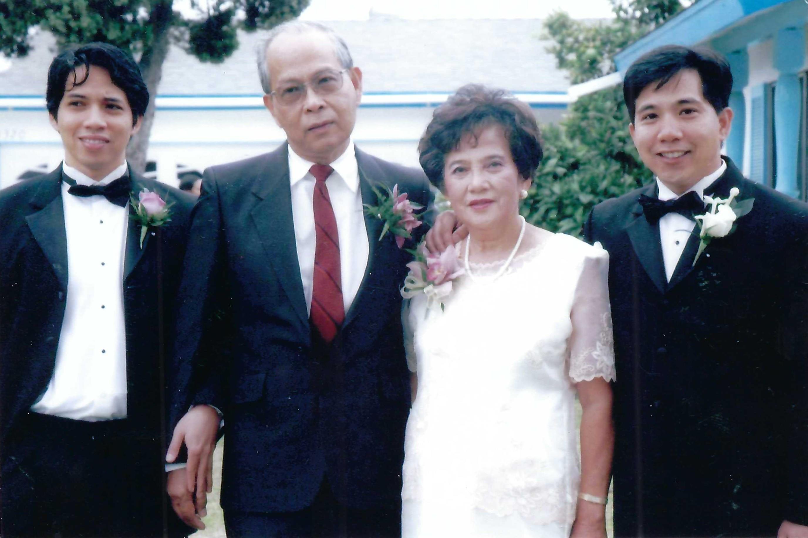 Four family members dressed in formal attire pose together in a garden, celebrating love and unity.
