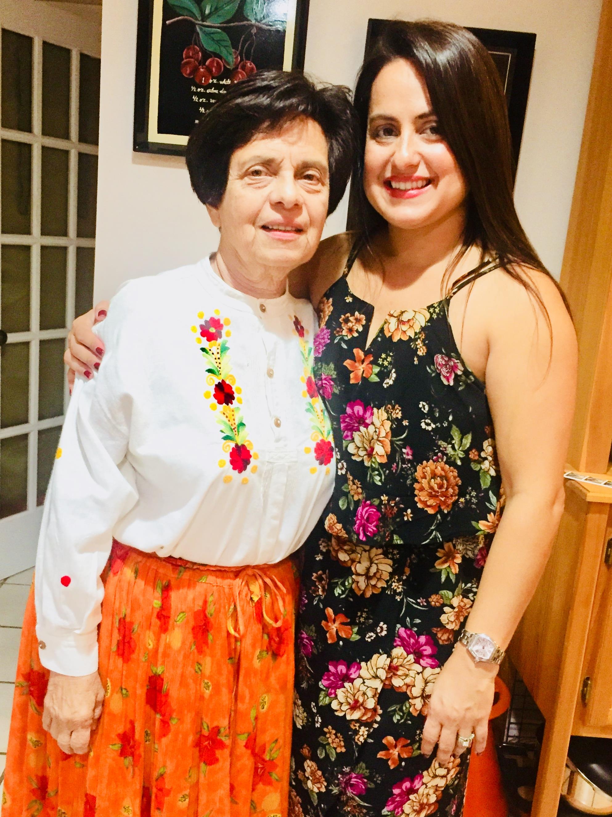 Women pose happily in colorful outfits, celebrating together in a comfortable indoor setting.