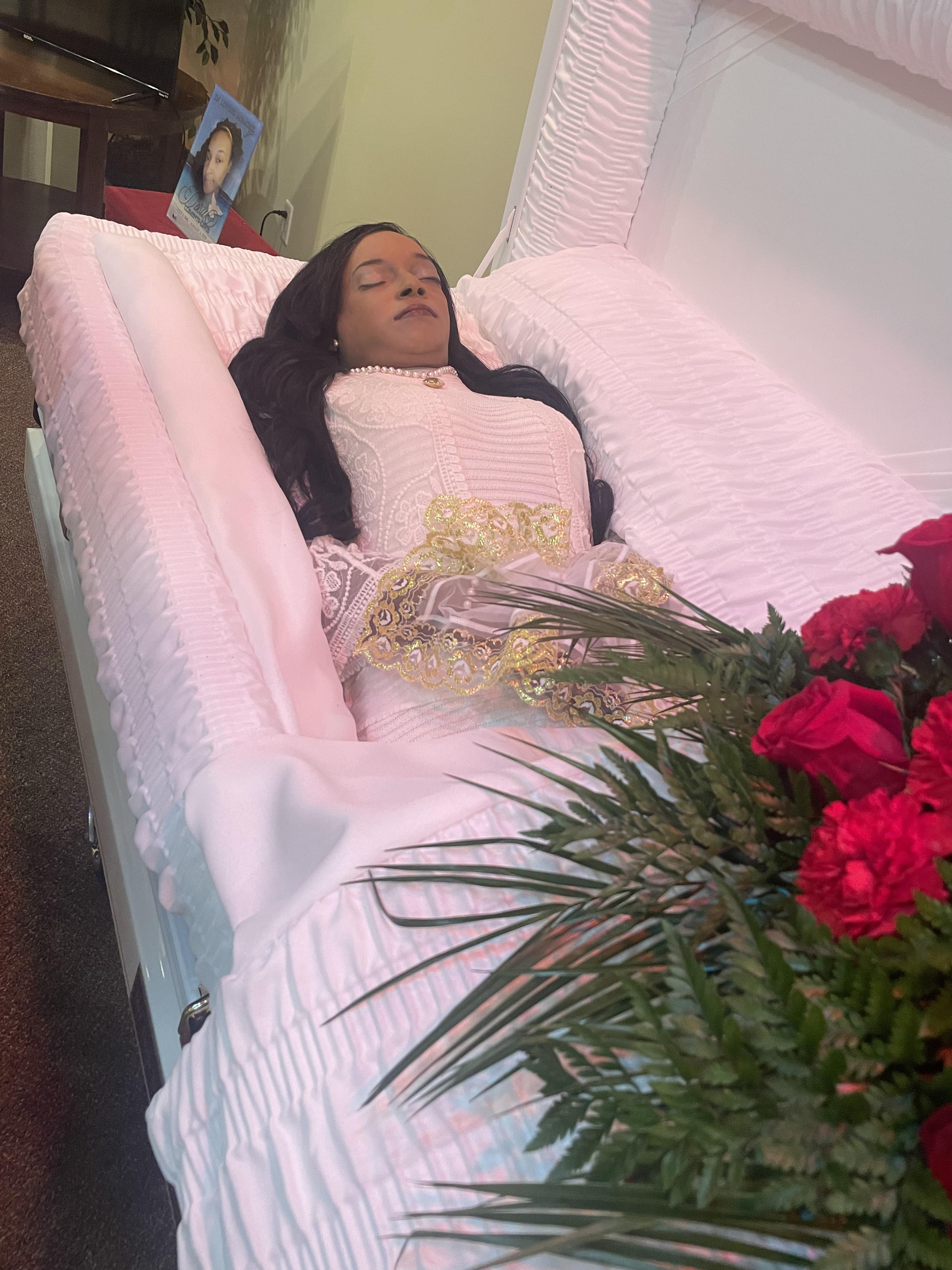 A woman lying in a coffin with flowers
