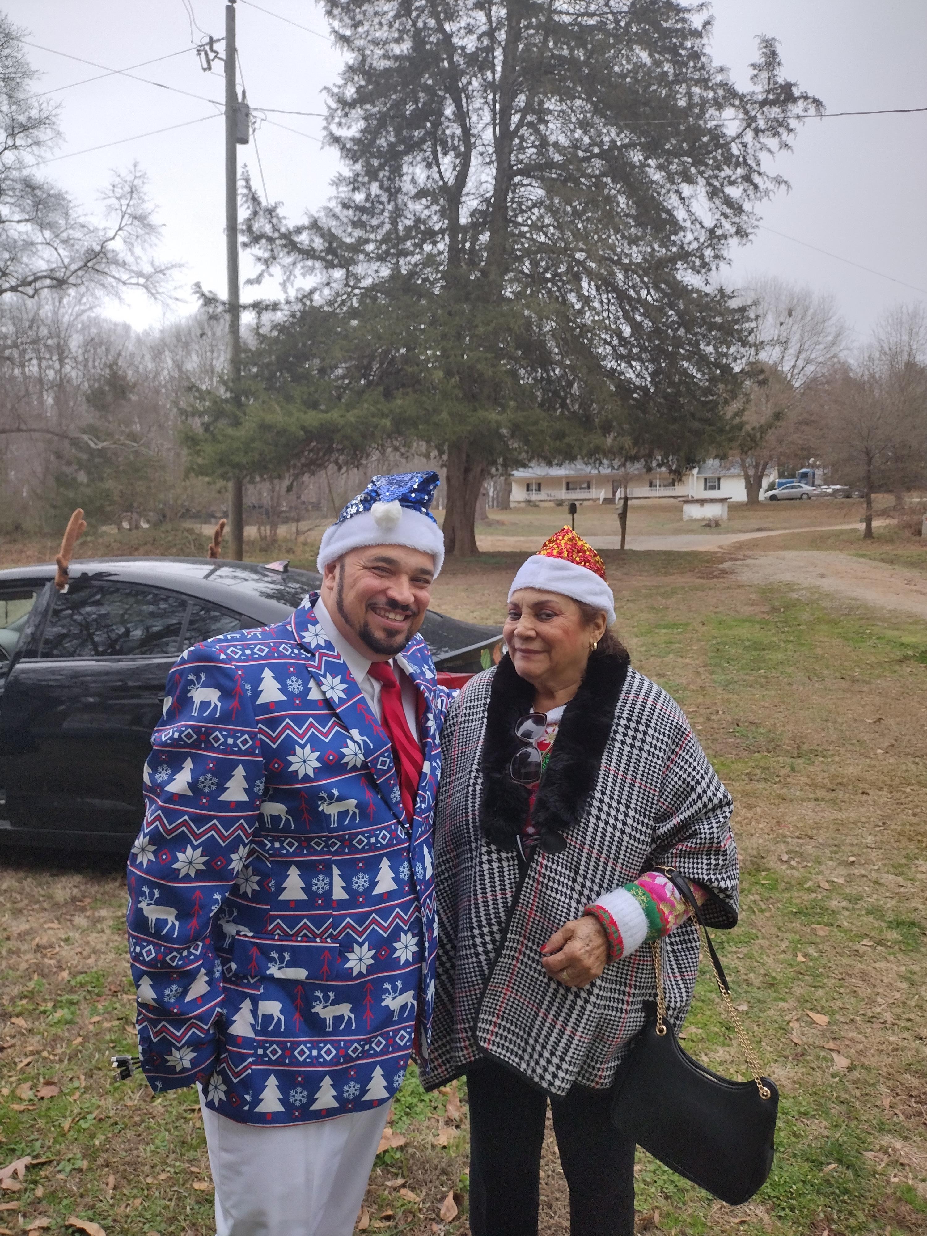 Friends celebrate winter festivities wearing colorful outfits and hats in a green outdoor setting.