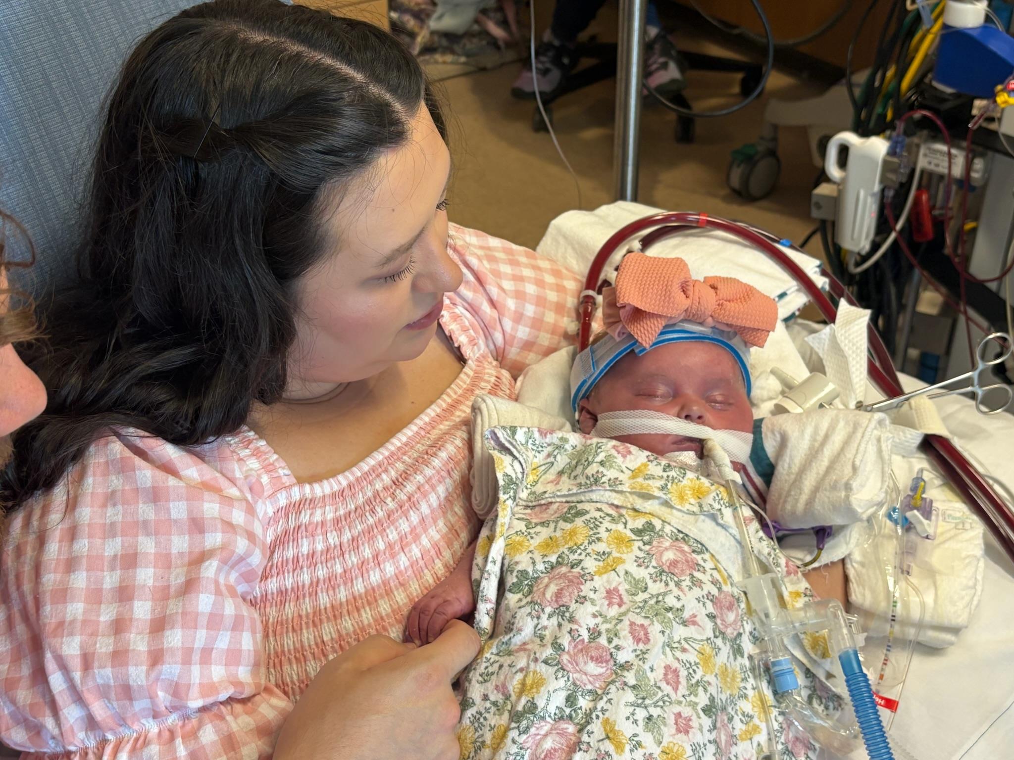A mother cradles her newborn in a hospital, capturing a tender moment of love and care.