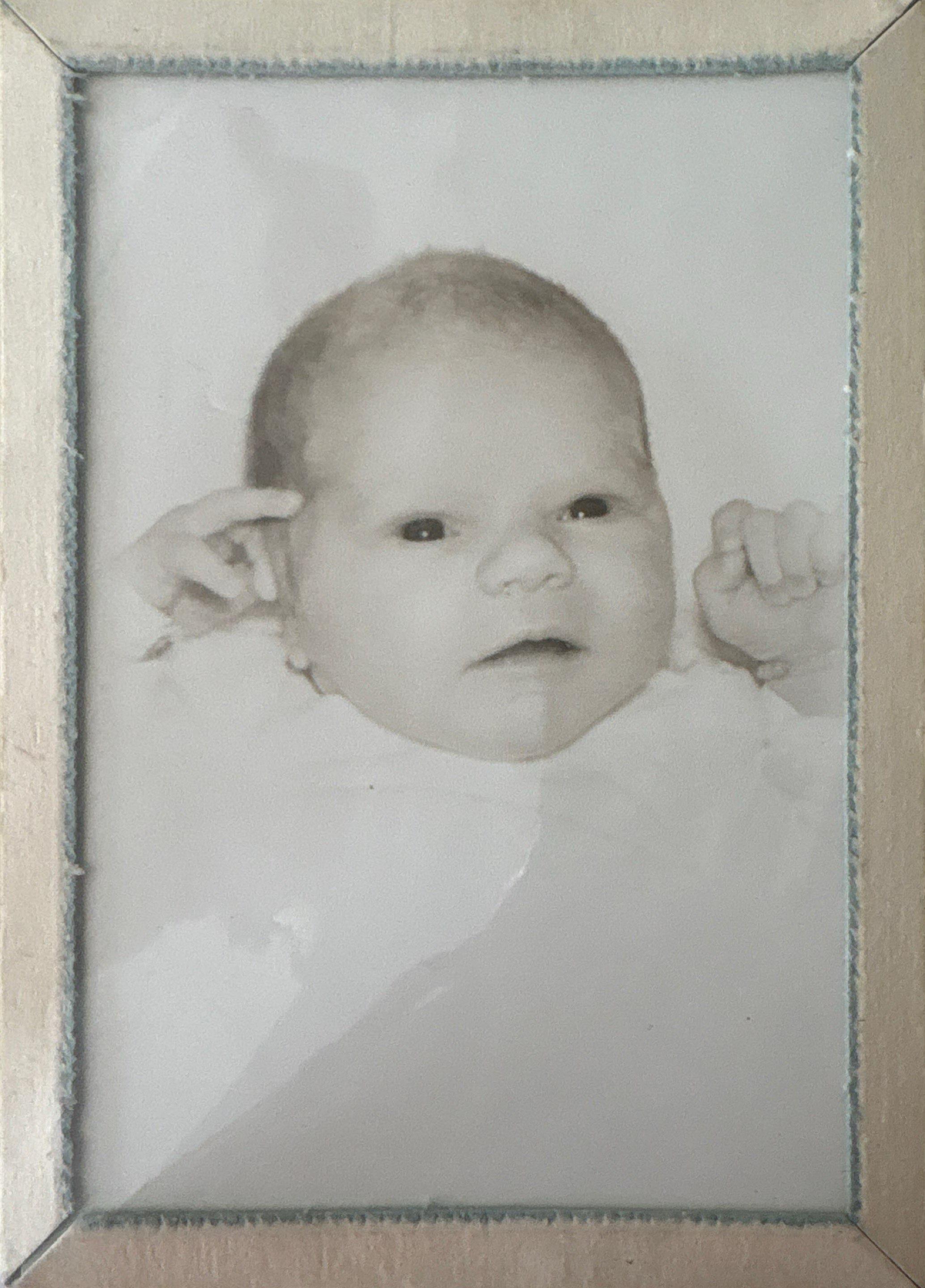 This black and white photograph features a baby with a thoughtful expression, framed beautifully.