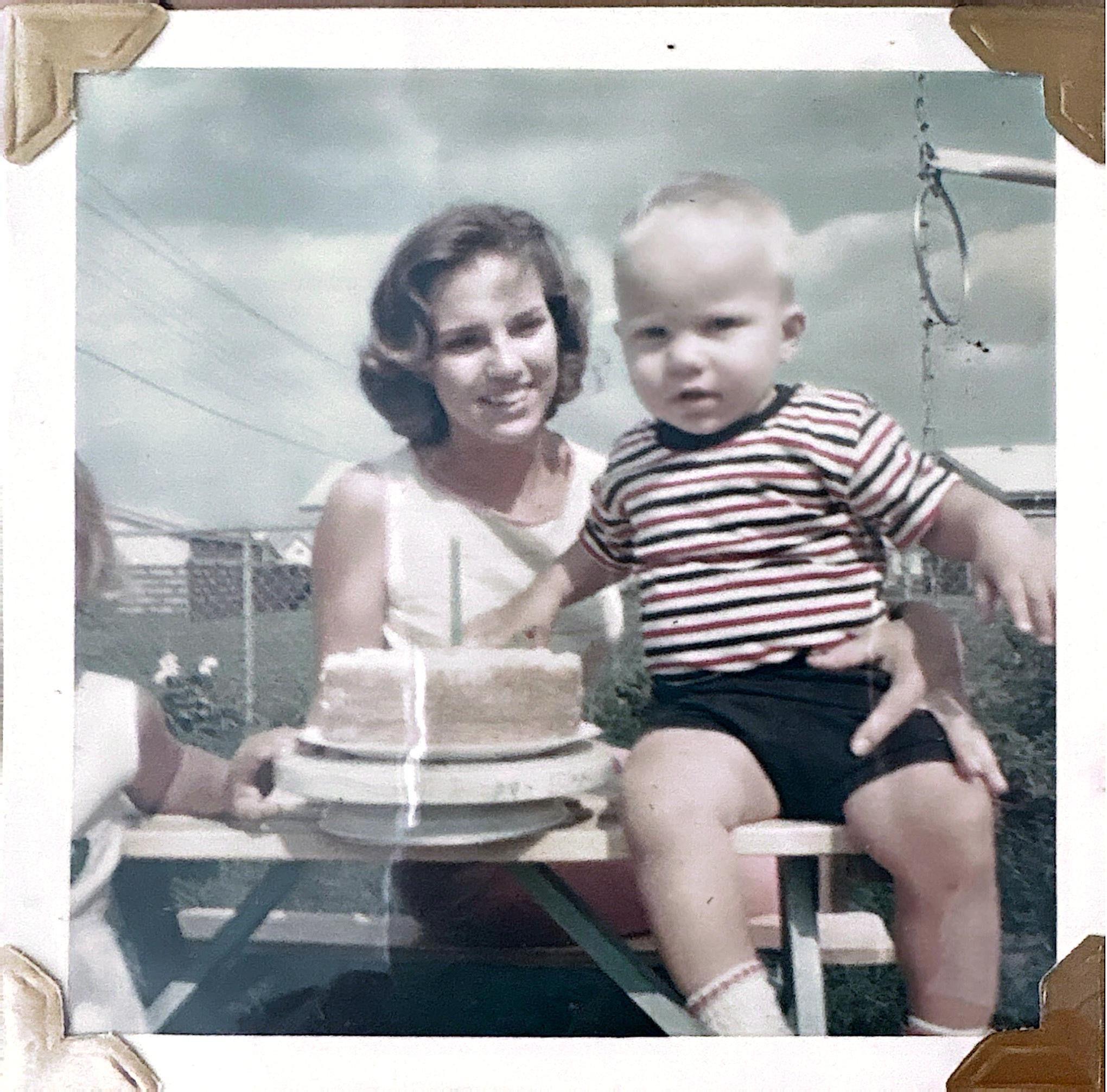 A woman and a young boy celebrate a special occasion with a birthday cake in the backyard.