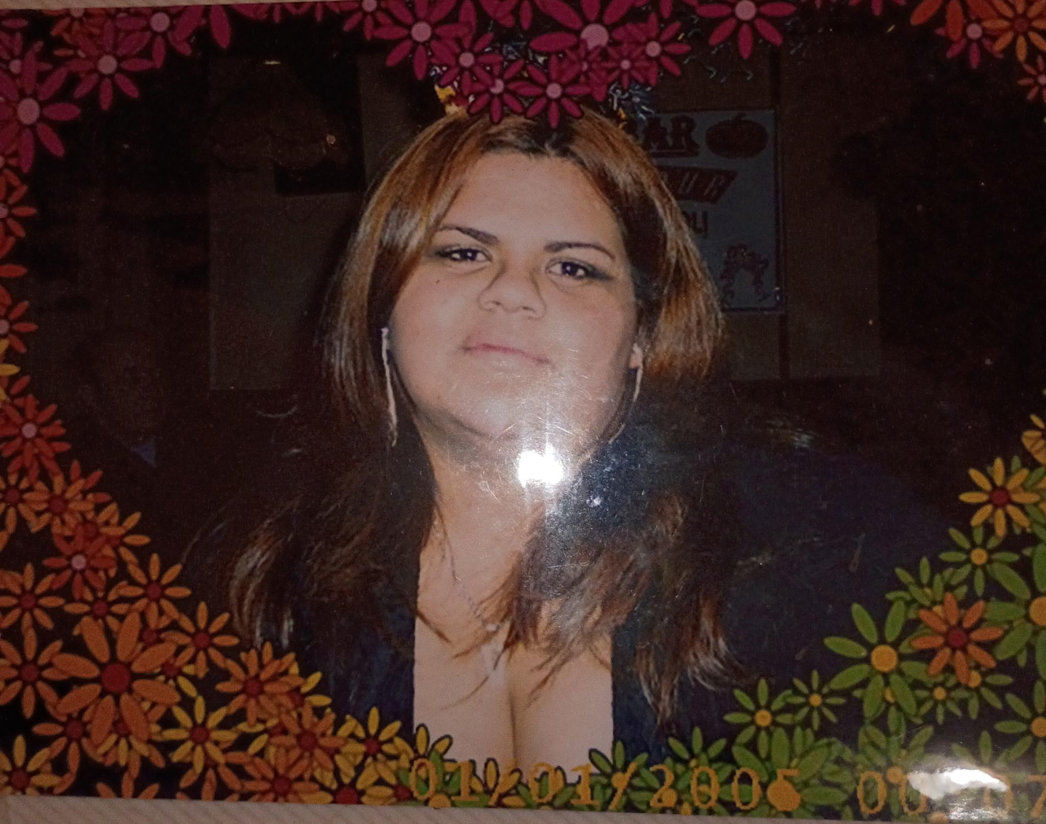 A woman smiles for the camera, framed by a colorful flower border indoors.