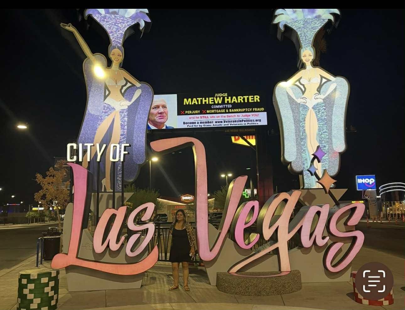 Visitors admire the colorful Las Vegas city entrance adorned with vibrant characters at night.