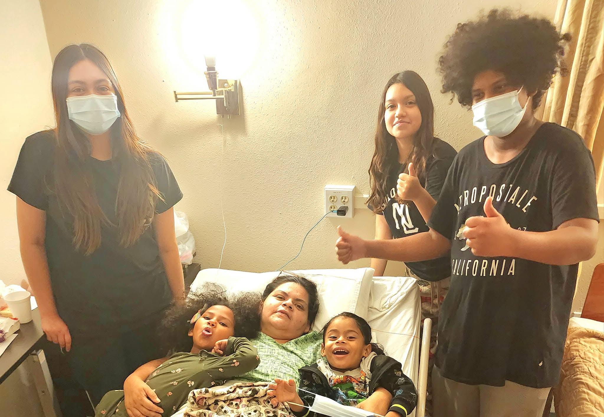 A family stands beside a patient in a hospital bed, displaying love and encouragement for recovery.