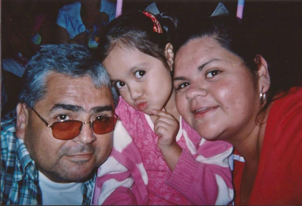 A family poses happily with a young girl making a playful expression, showcasing love and joy.