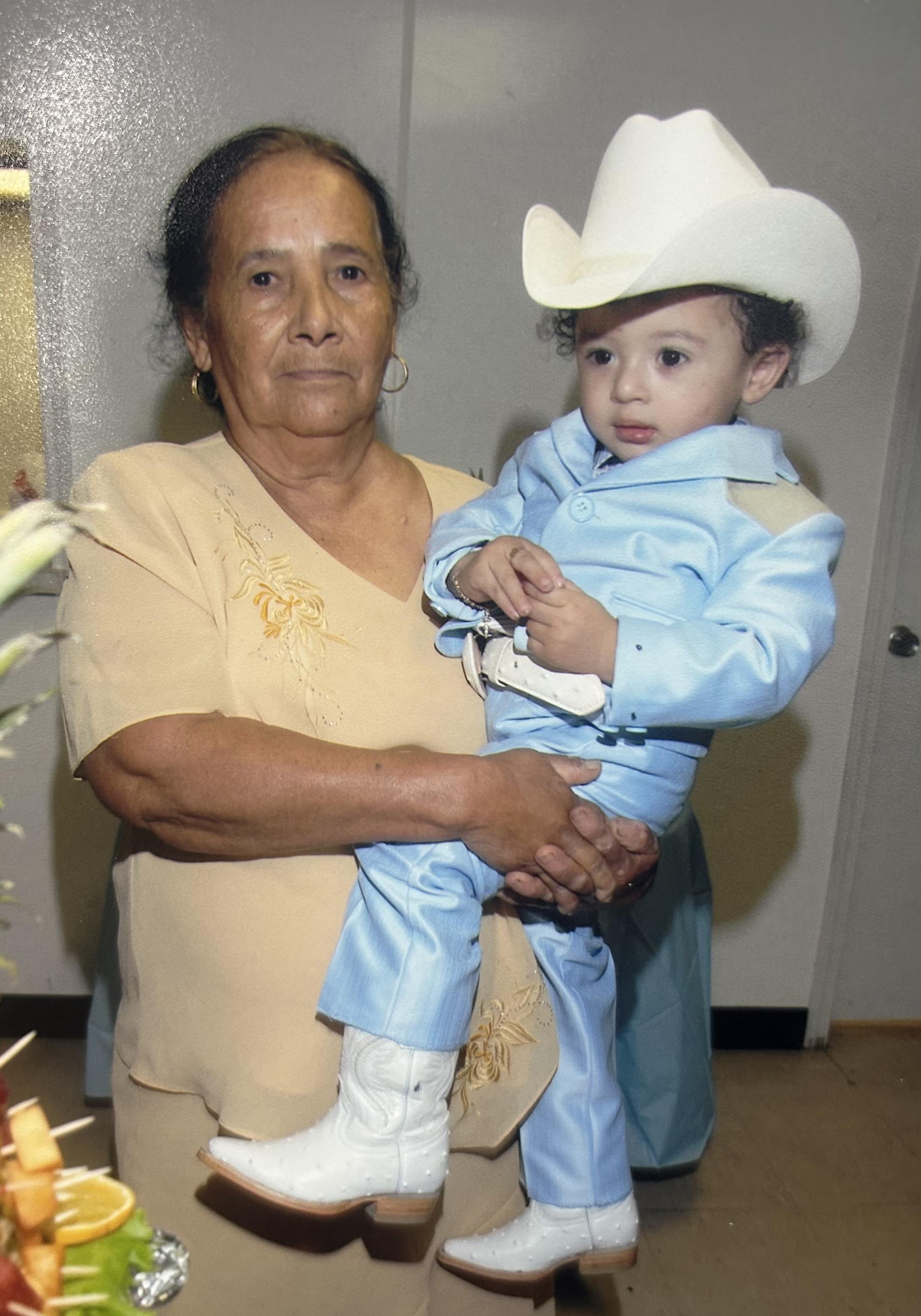 A woman embraces a young boy dressed in a blue cowboy outfit during a family celebration.
