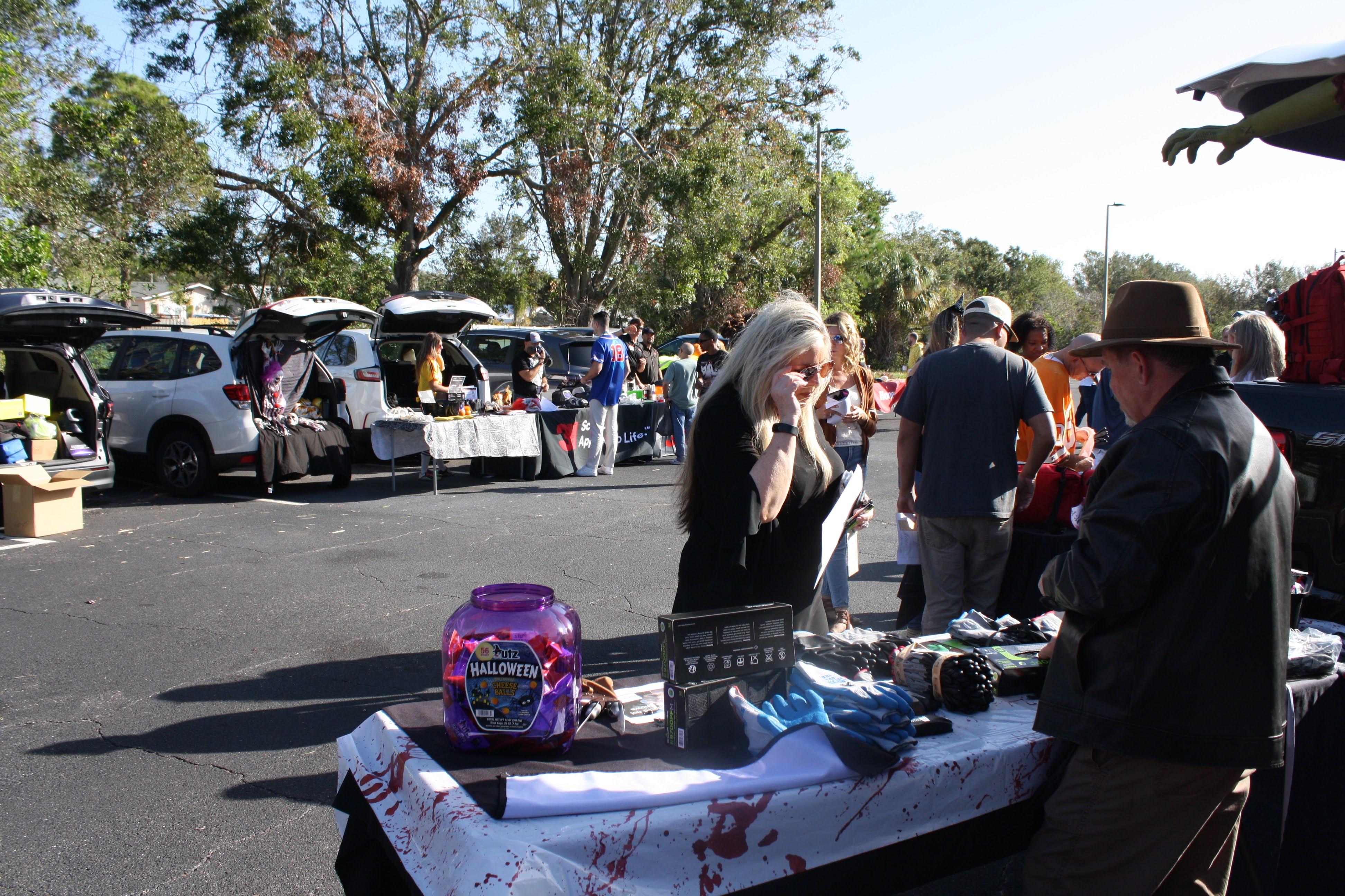 Many people are browsing various stalls while enjoying a sunny day at a lively market.