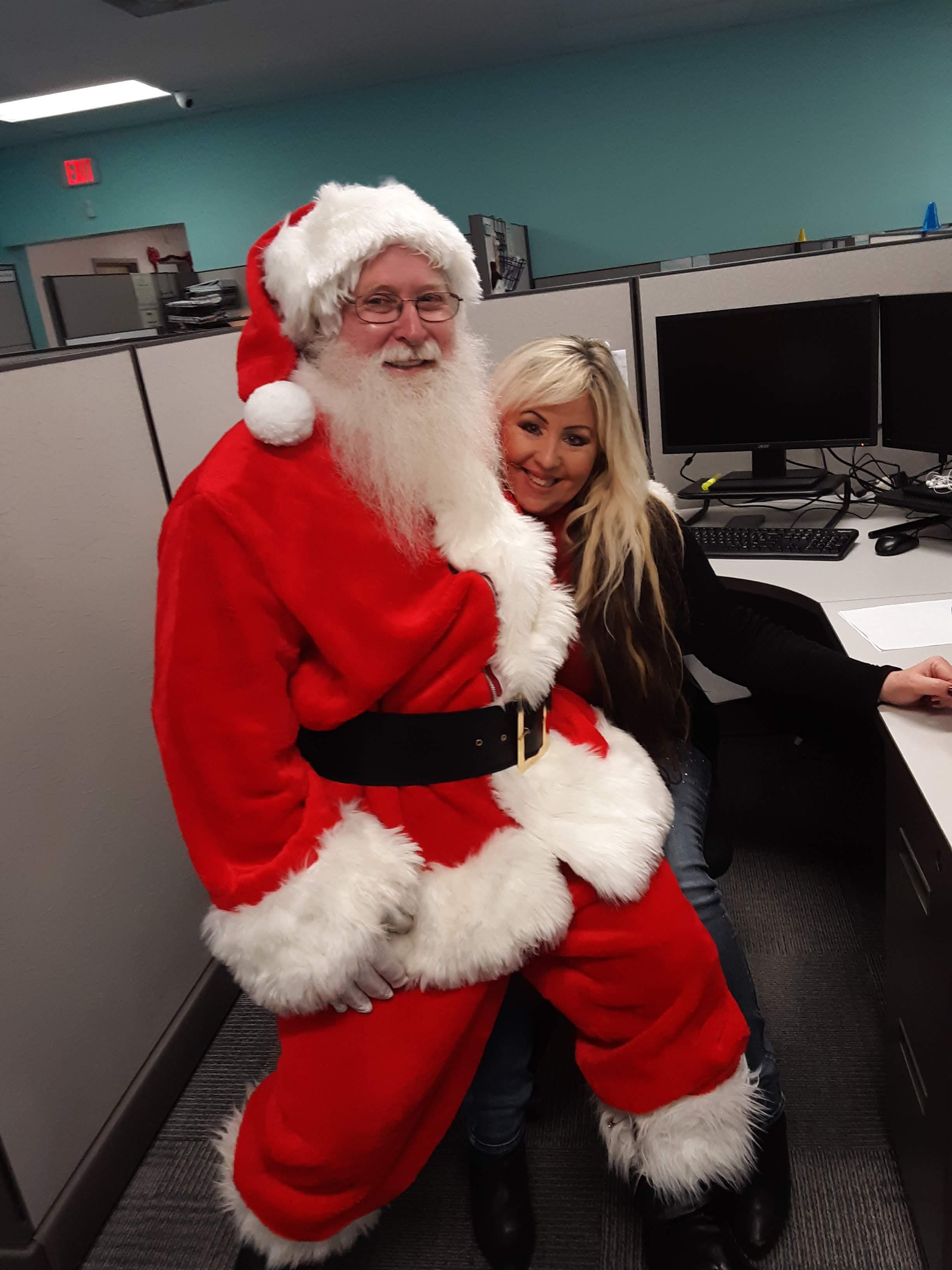 Santa brings holiday cheer to the office, celebrating with excited employees and spreading joy.