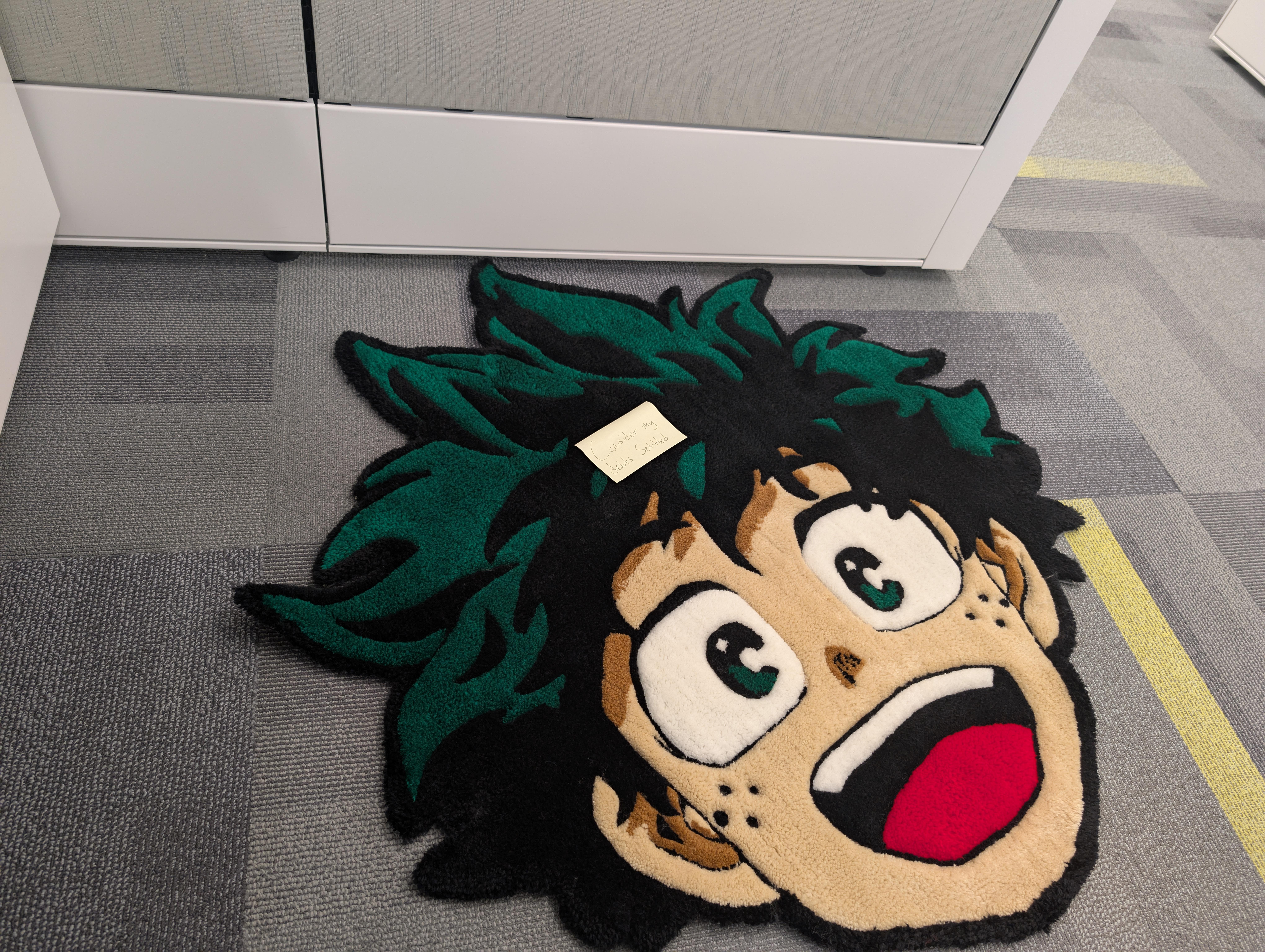 A vibrant rug displays a smiling anime character with spiky green hair in an office area.