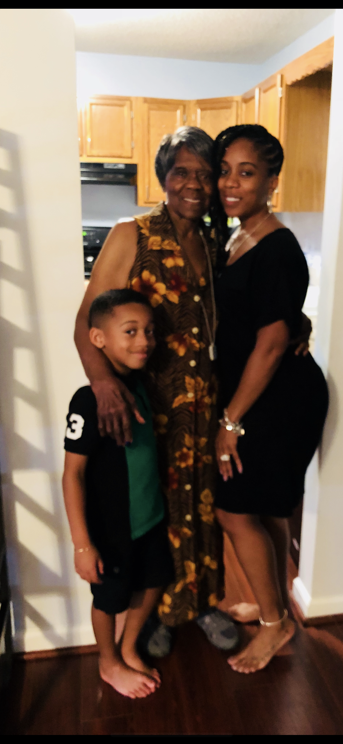 Three family members, including a young boy, share a joyful moment at home.