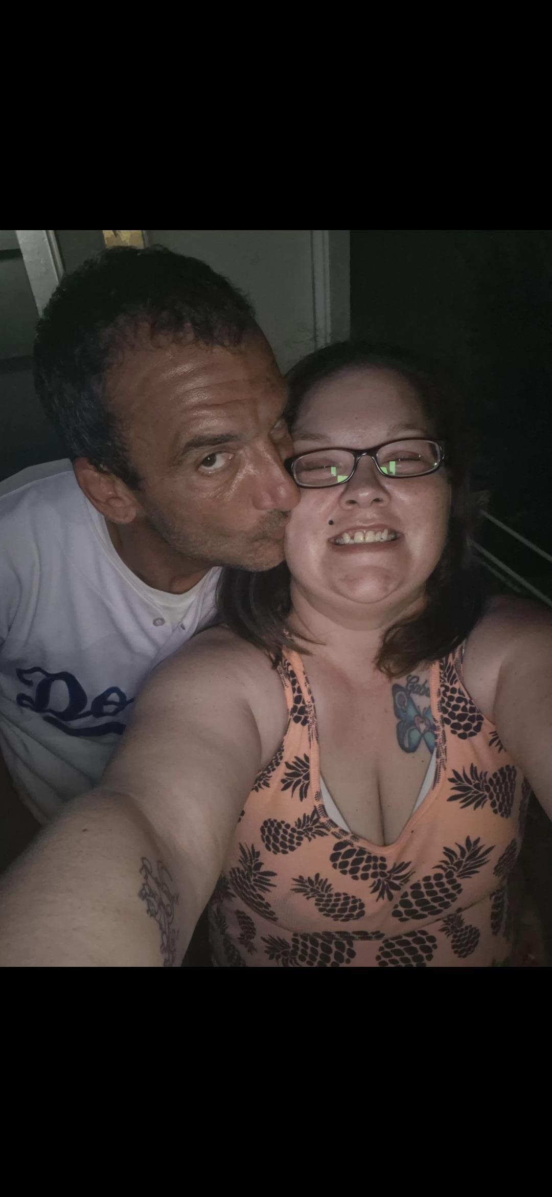 A couple enjoys a close moment while taking a selfie, smiling and sharing affection indoors.