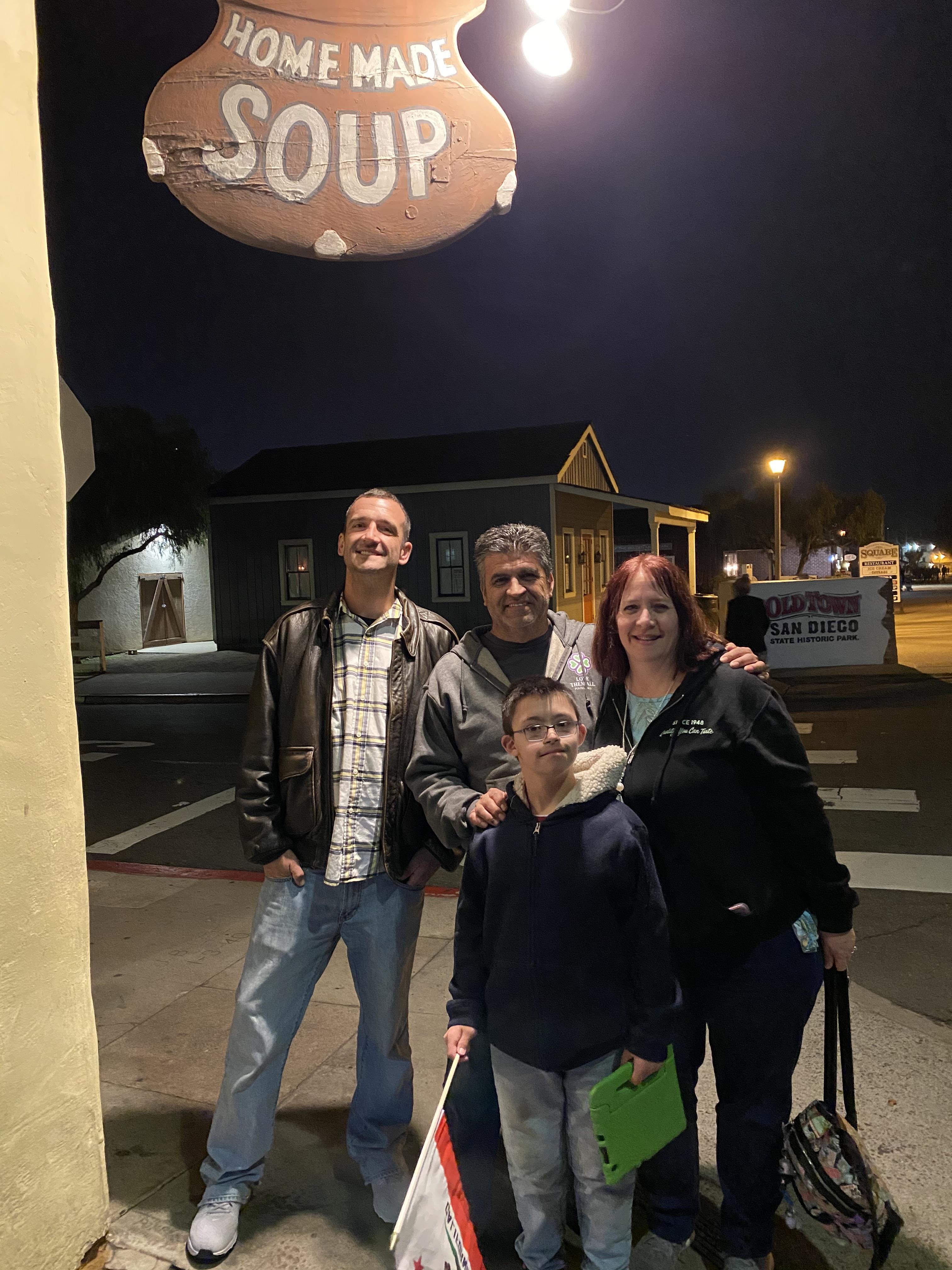 A family poses together in front of a cozy restaurant at night, smiling and enjoying their time.