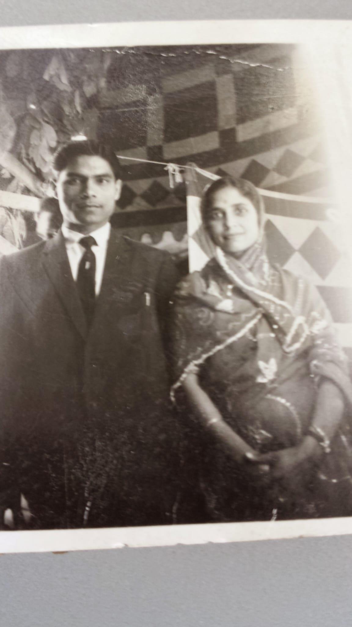 A man and woman are dressed in traditional Indian clothing, smiling together at a festive event.