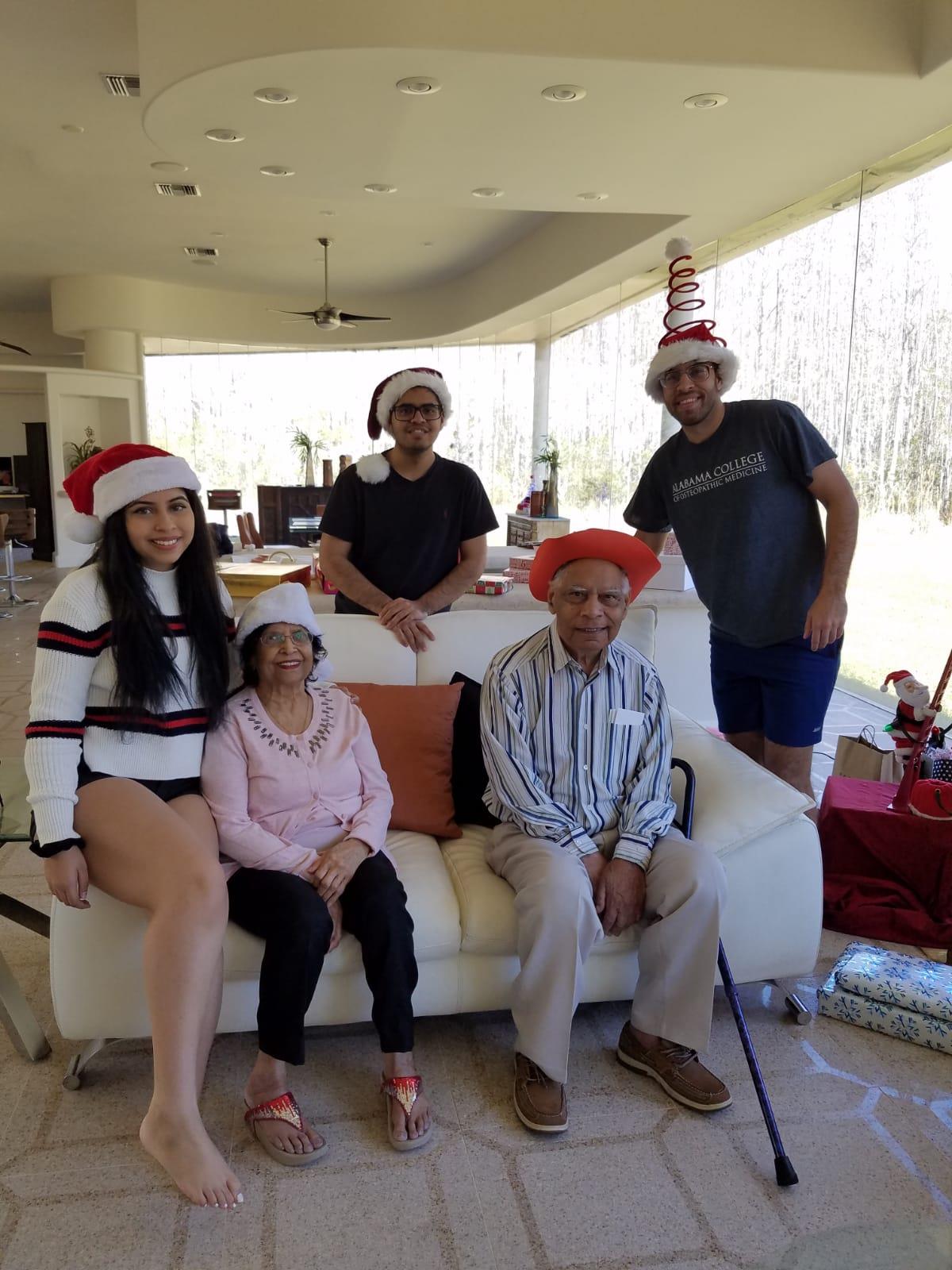 A cheerful family is celebrating Christmas, wearing festive hats and enjoying each other's company.