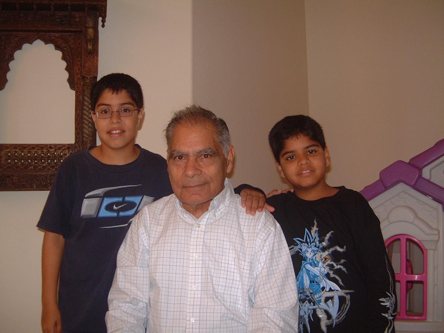 Grandfather poses with his grandsons, smiling happily during a family event in their living room.