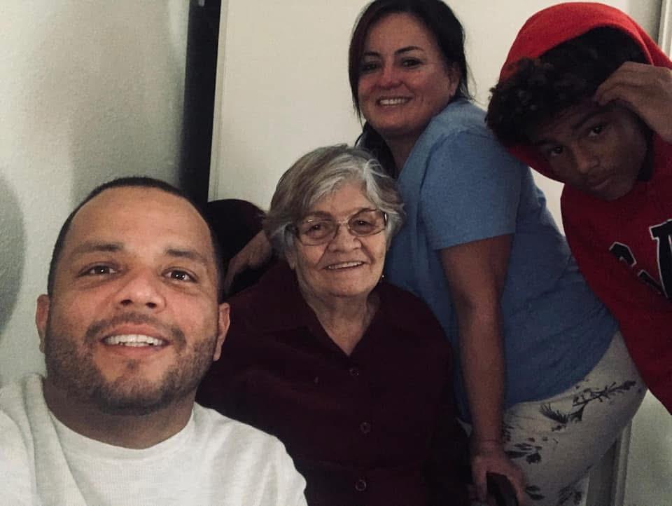 Family members share smiles and warmth while visiting their elderly relative at home.