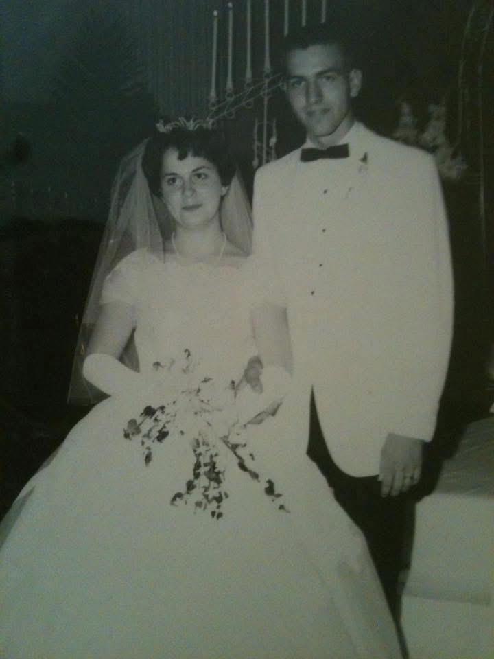Newlyweds stand together, dressed elegantly, surrounded by decor celebrating their commitment.