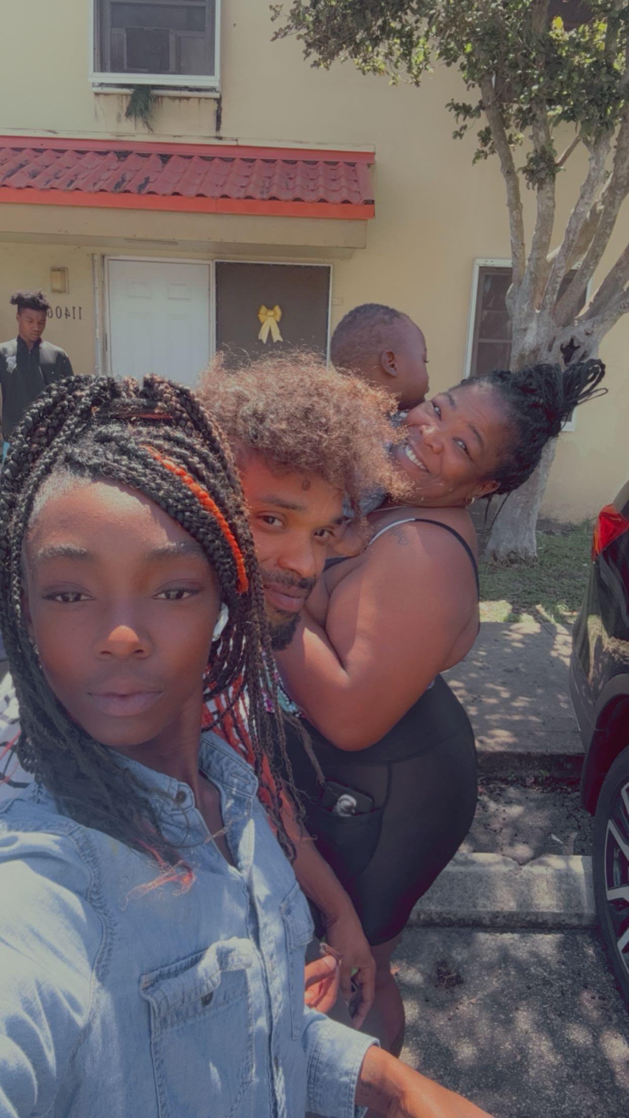 Friends gather outside, laughing and taking selfies while enjoying a bright day.