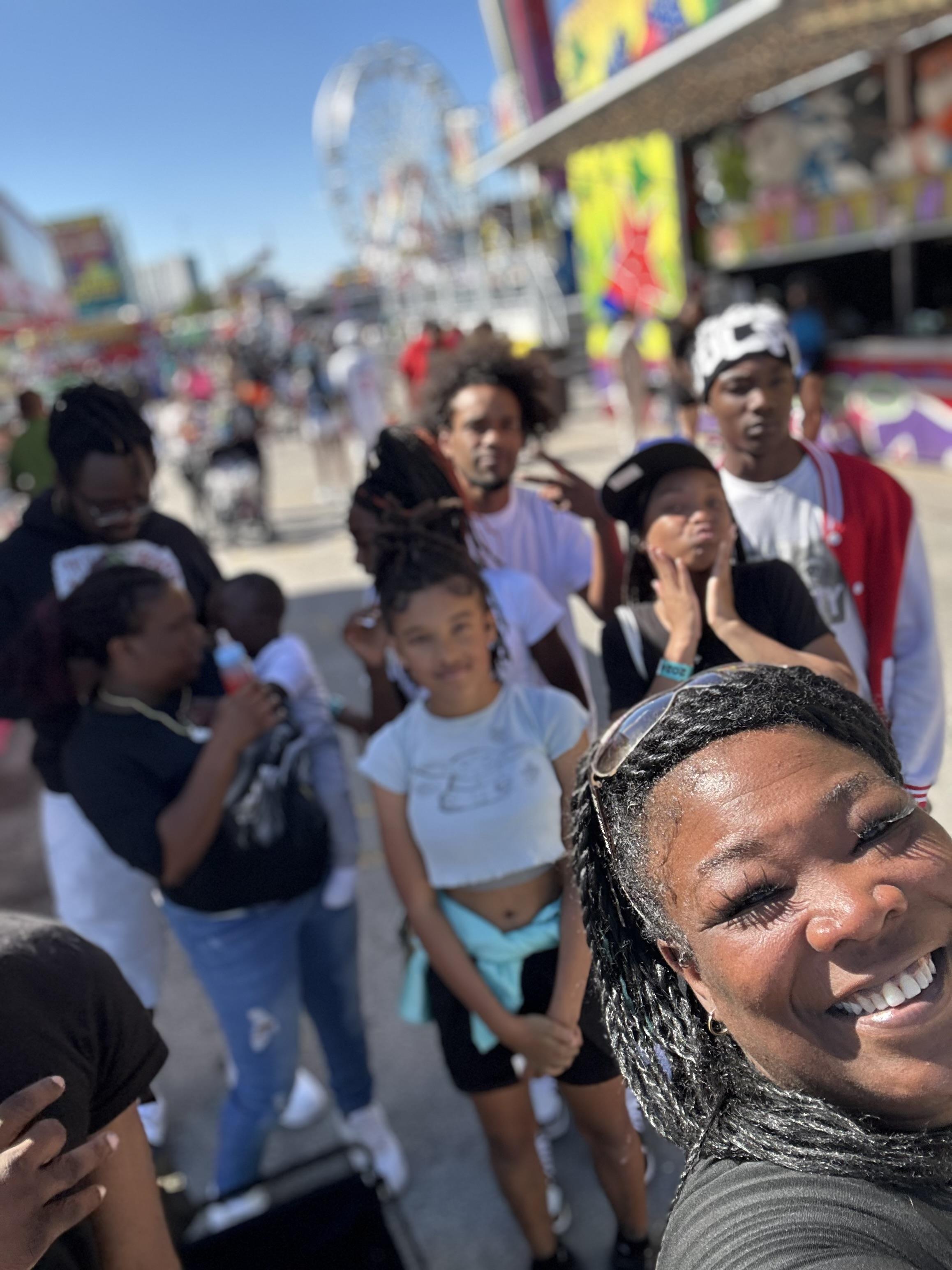 Friends gather at a fair, sharing smiles and laughter while enjoying the vibrant atmosphere.