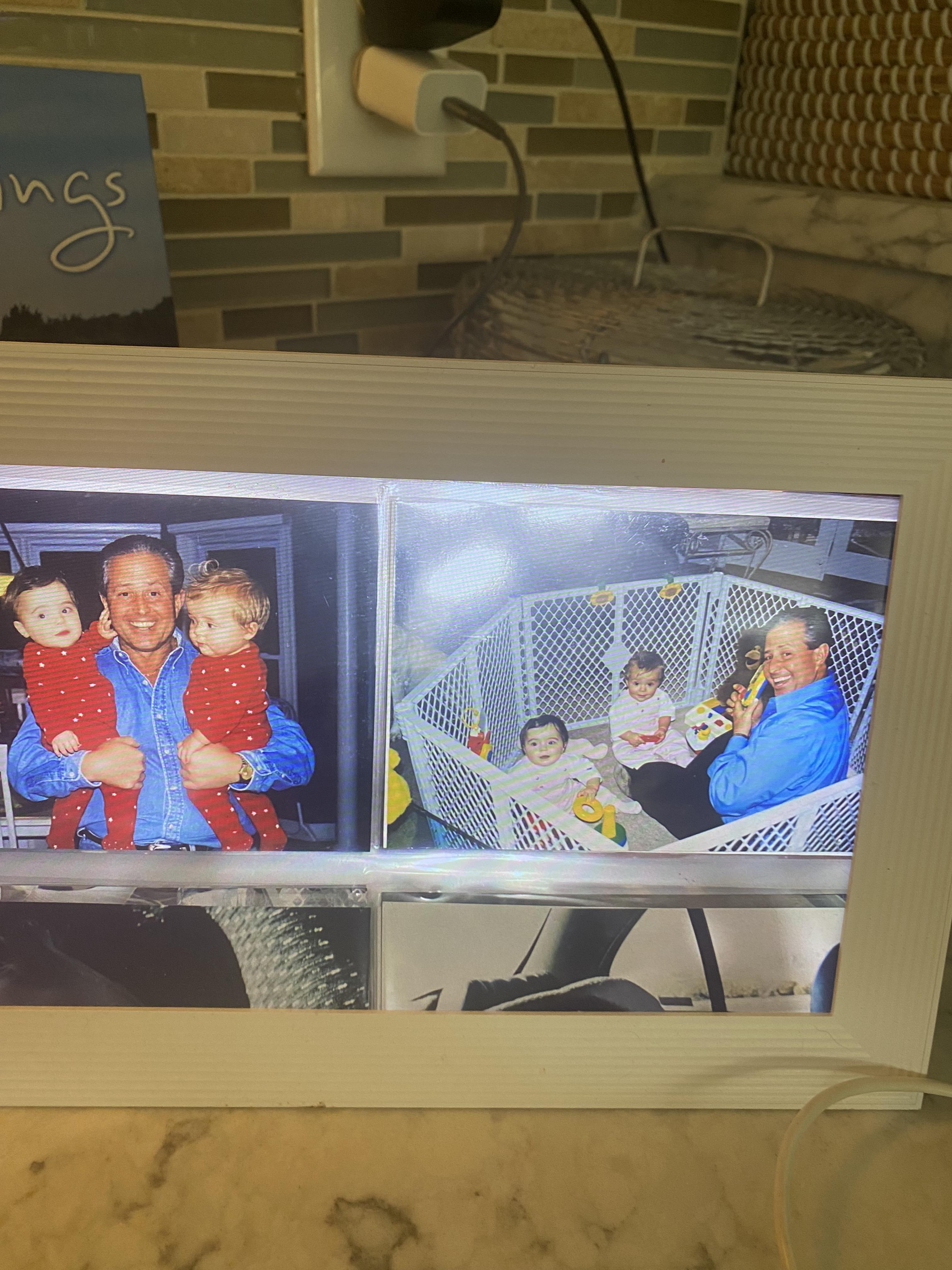 A man holds twin children in red outfits while sharing smiles and laughter indoors.