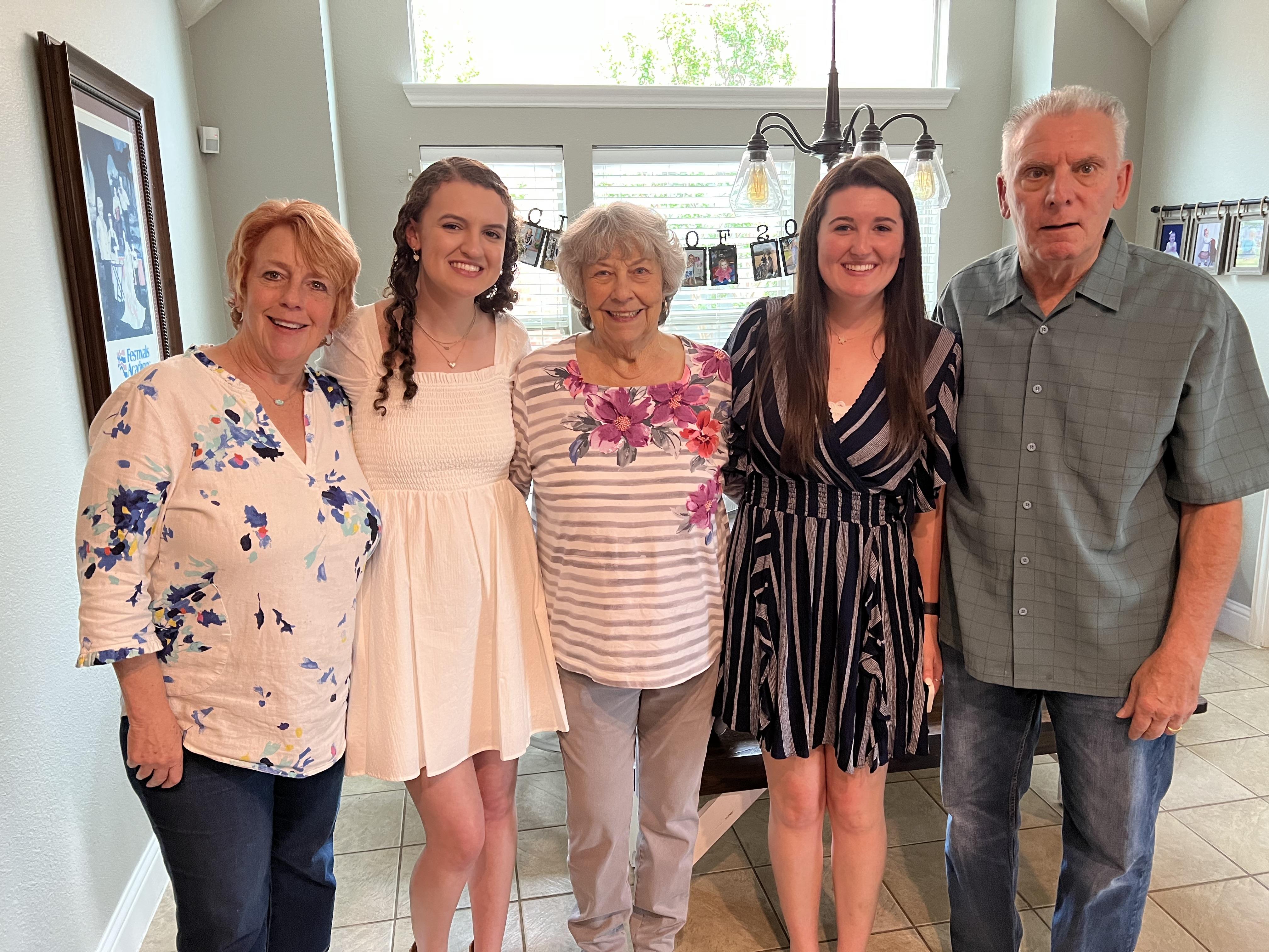 A joyful family group stands together in a well-lit kitchen, celebrating a special occasion.