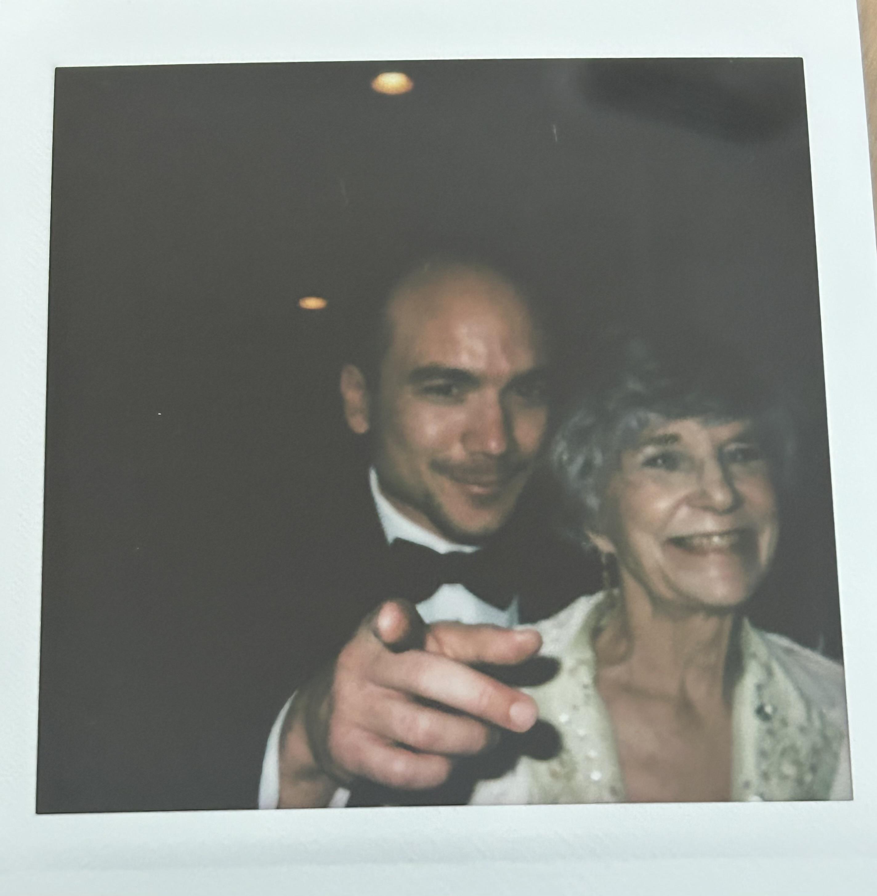 Two people smile and enjoy each other's company, dressed elegantly at a festive event.