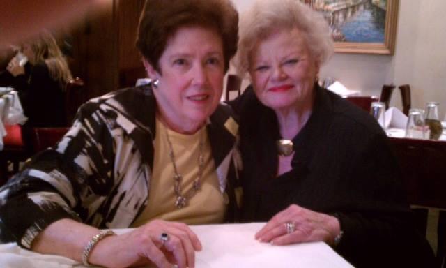 Two women pose happily at a restaurant table, enjoying each other's company during lunch.