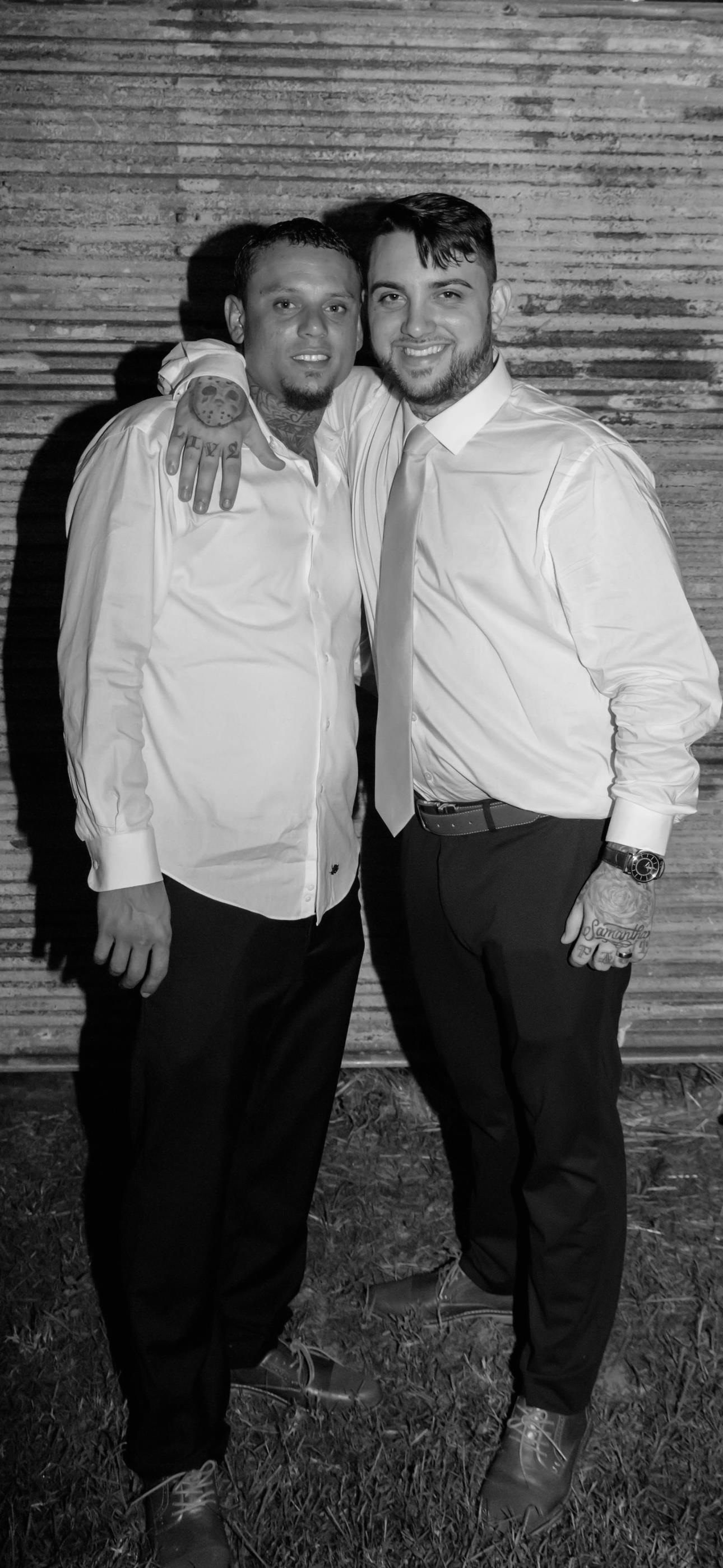 Men dressed in formal shirts enjoy a warm moment, posing closely together outdoors.