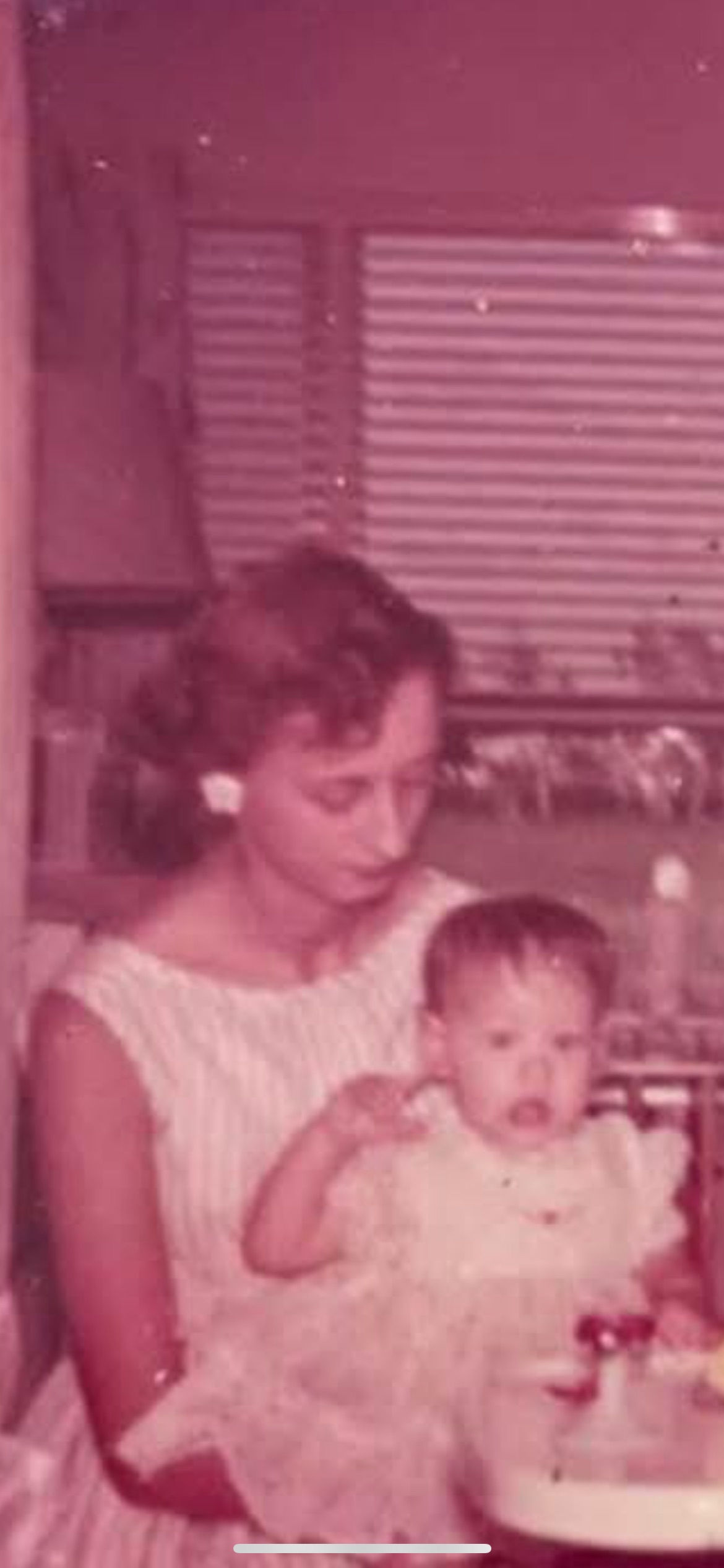 A mother gently holds her baby while seated in a cozy kitchen, showcasing love and care.