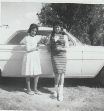 A couple of women standing next to a car