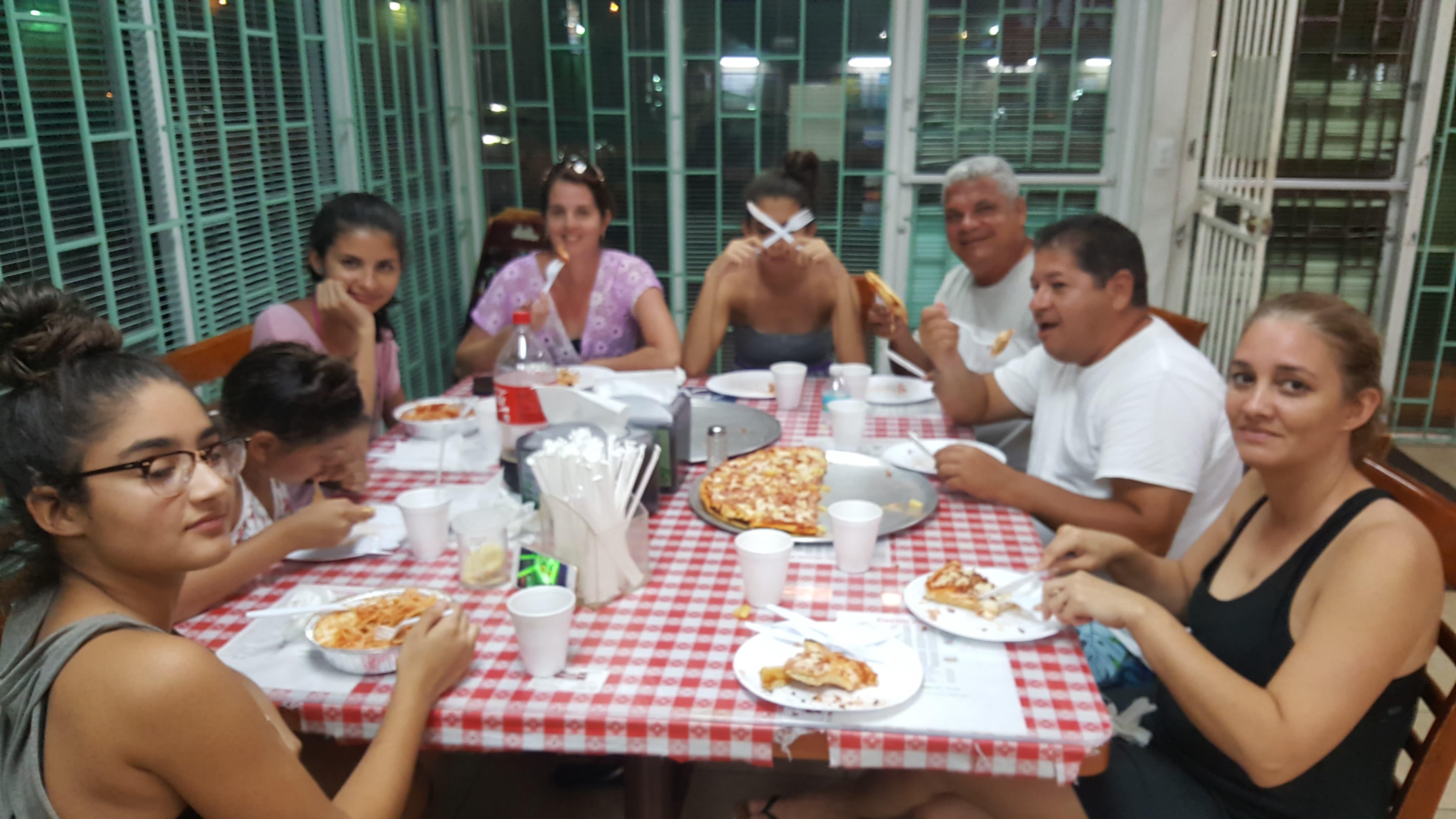 Friends enjoying a joyful pizza dinner at a table with a checkered cloth.