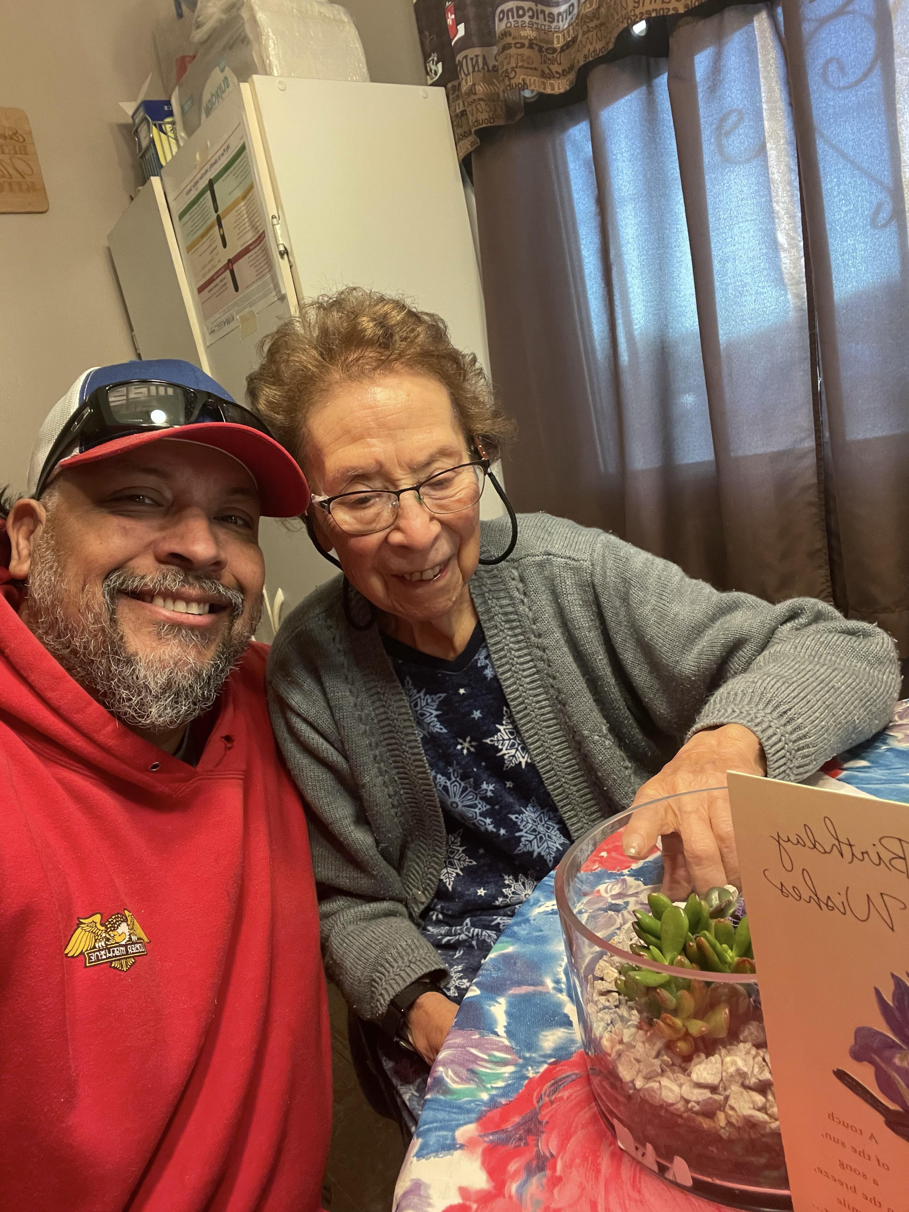 A joyful moment shared between a man and an elderly woman in a homey environment.