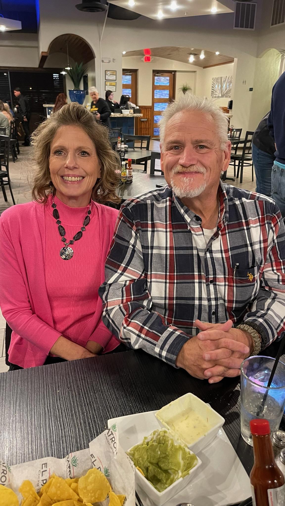 Two people sit closely together, smiling and enjoying each other's company at dinner.