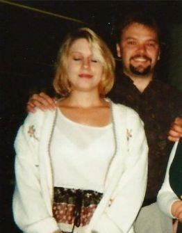 Two individuals stand closely, sharing smiles and displaying a relaxed atmosphere during nighttime.