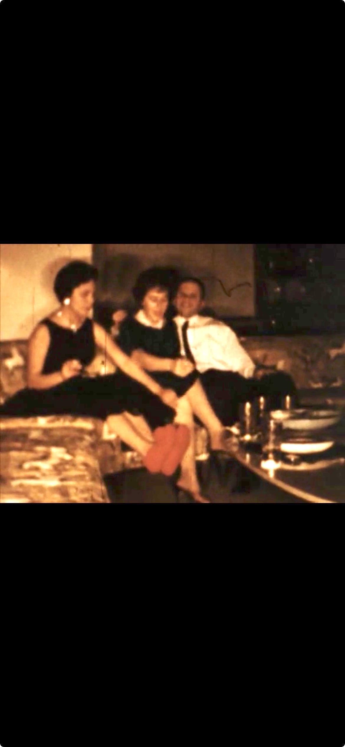 Three friends relax and chat on a vintage sofa in a warm, inviting living room.