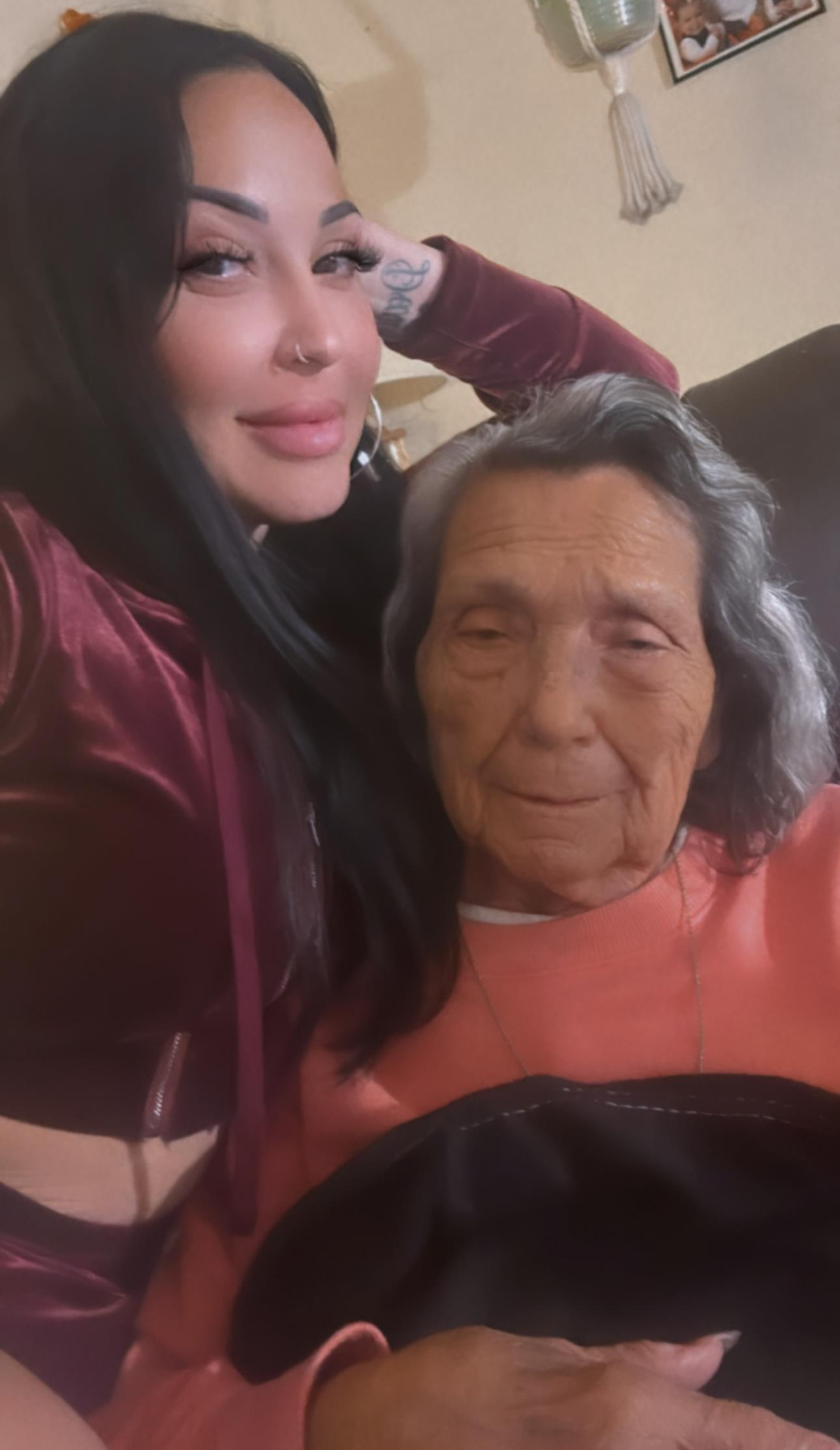 Two women pose closely together, radiating joy in a comfortable living space filled with warmth.