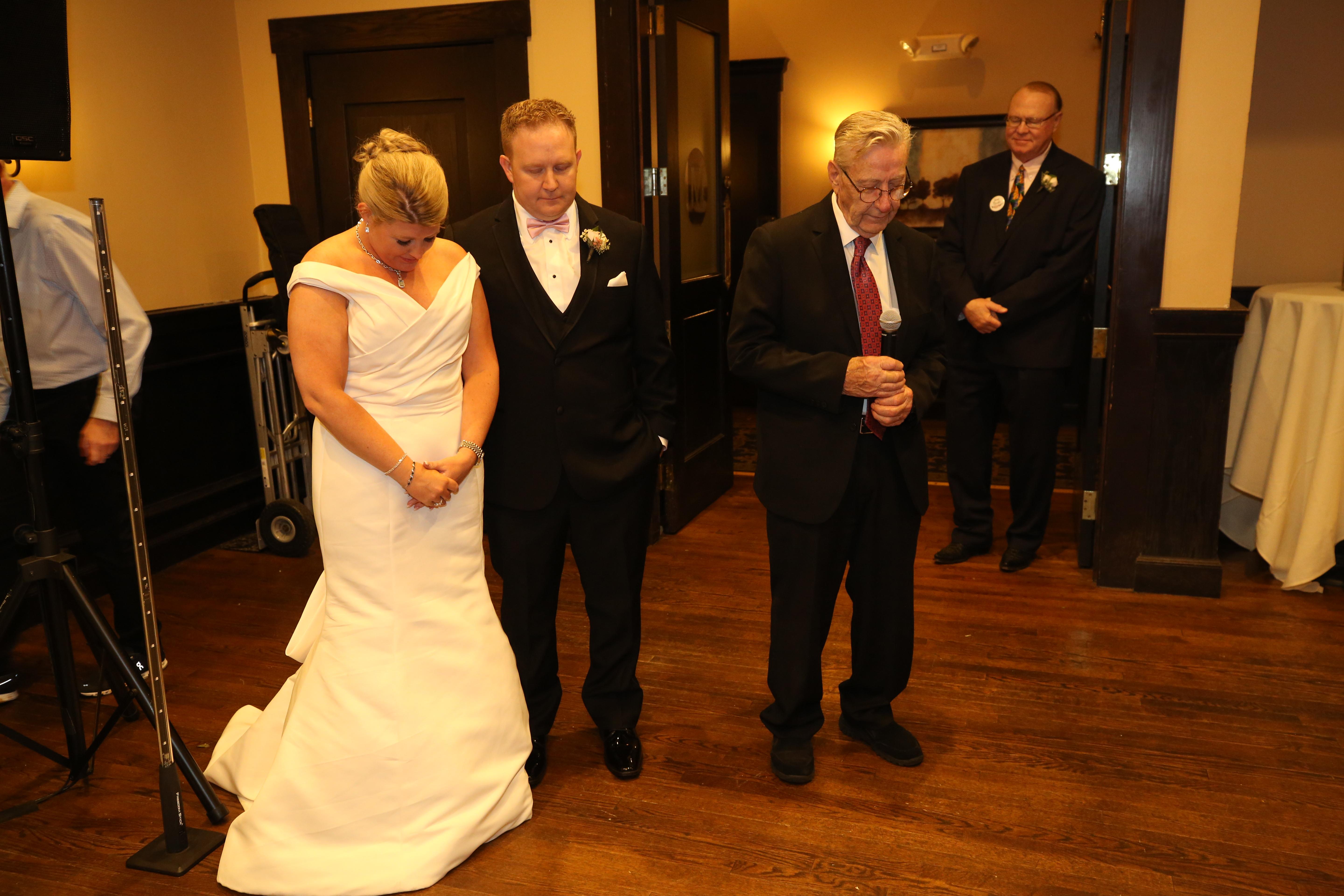 The bride and groom share a heartfelt moment together in a chic venue with heads bowed.