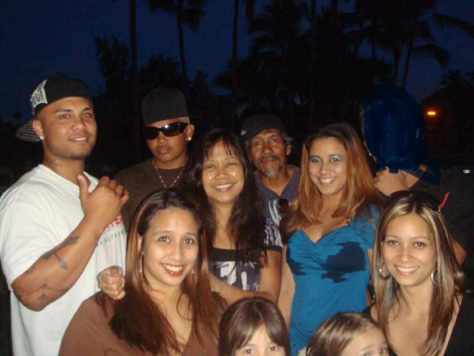 Group of friends smiling and posing together during an evening celebration under a setting sun.