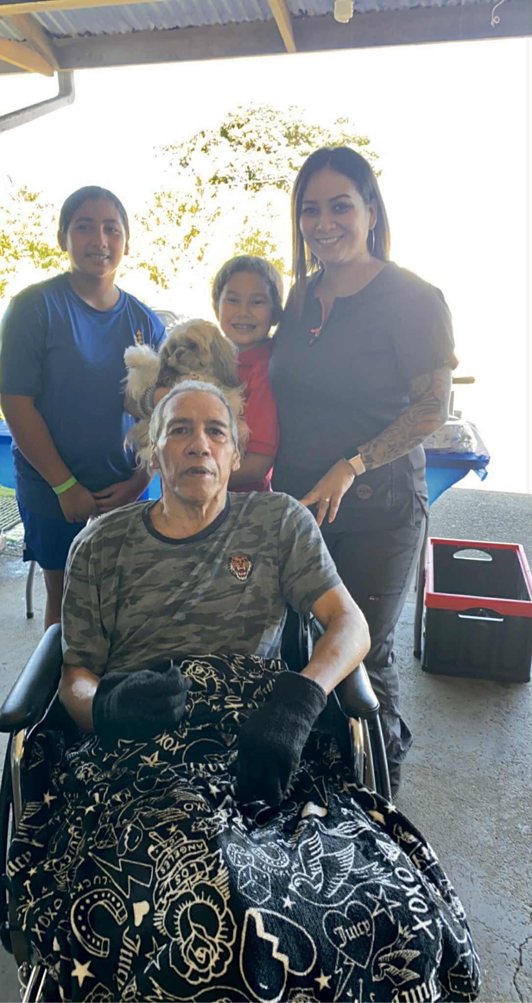 Four family members share a sunny day in the park, smiling together.